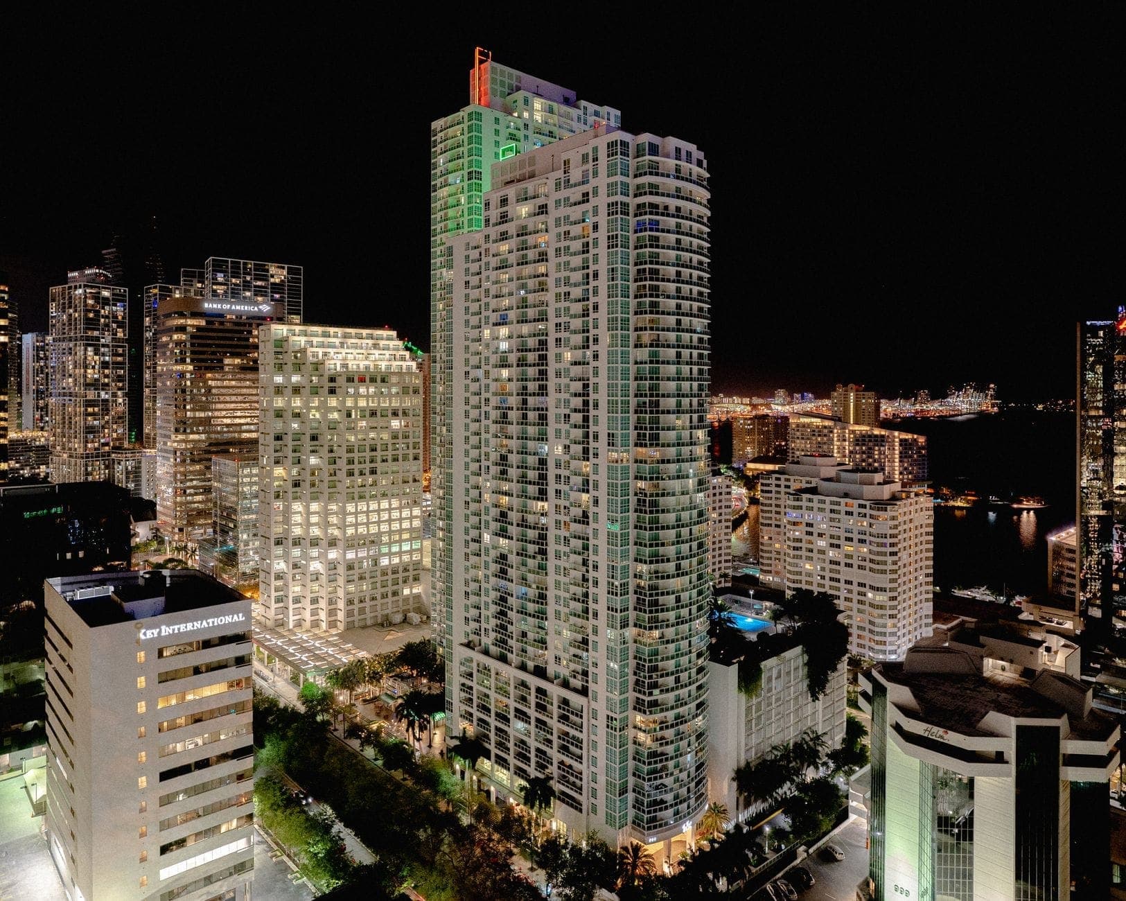 Ночной вид с воздуха на высокие современные небоскрёбы Downtown Miami и Brickell, ярко освещённые и окружённые городскими улицами.