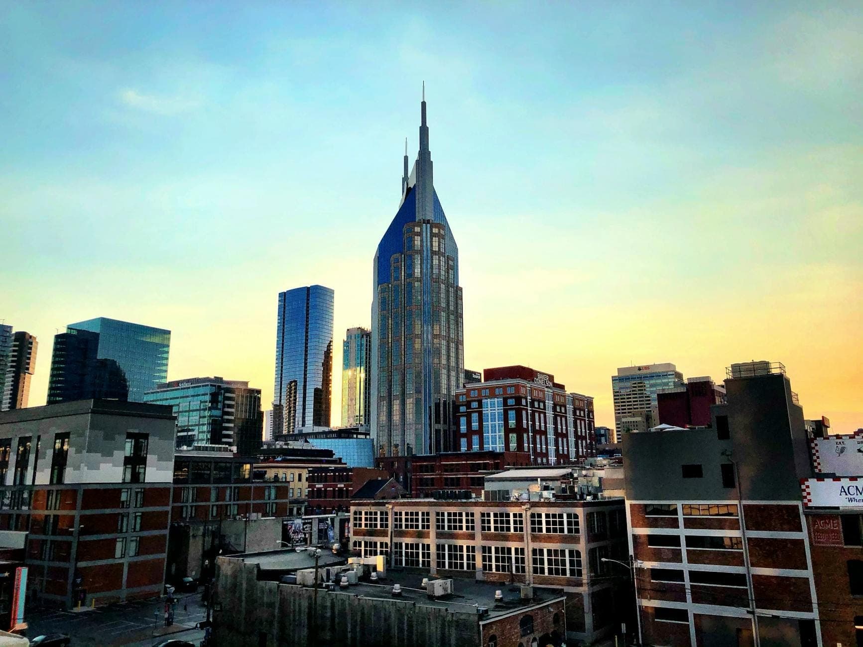 Skyline view of the Gulch area in Nashville at sunset, featuring modern high-rises and iconic buildings with a colorful evening sky.