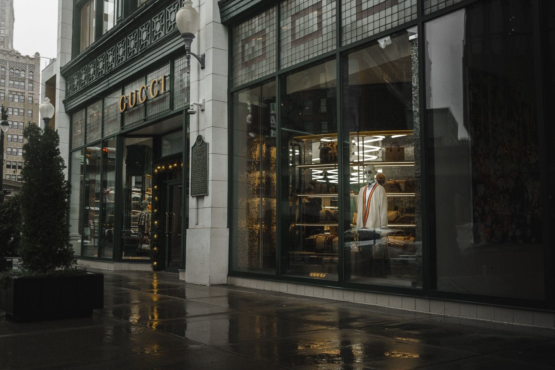 Upscale Gucci storefront with mannequins and a stylish window display on a wet street, evoking Yorkville luxury in Toronto.
