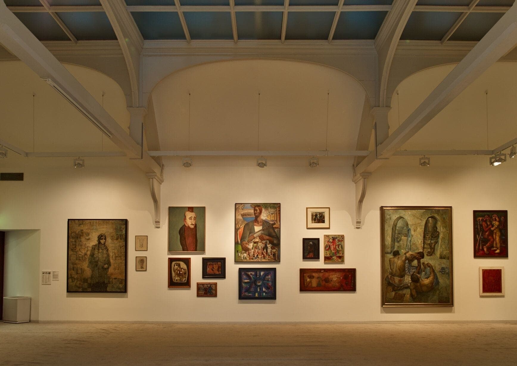 Vue large d'un mur d'exposition à la Whitechapel Gallery, présentant diverses œuvres d'art contemporain sous de hauts plafonds voûtés et un éclairage doux.