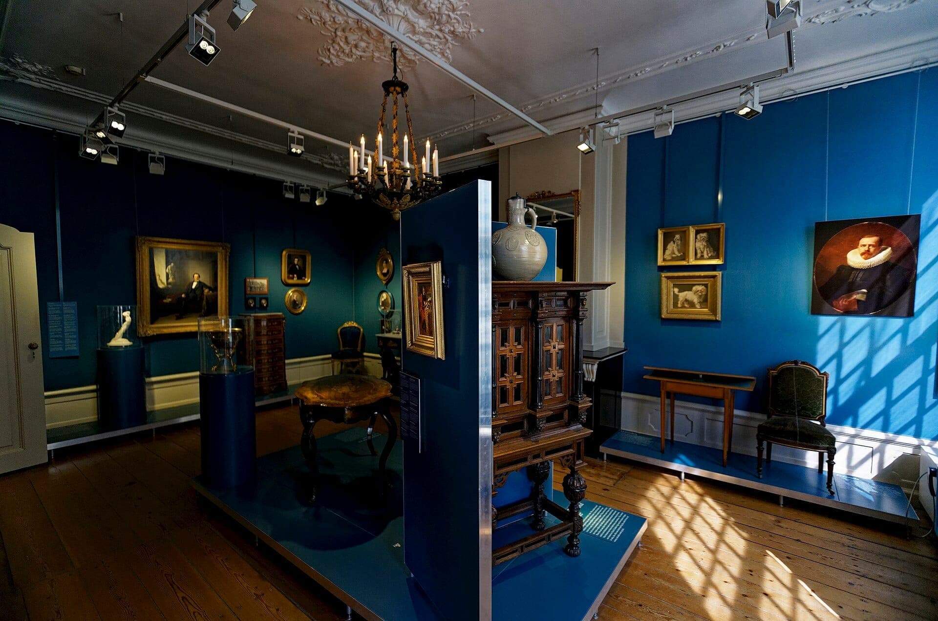Innenraum des Willet-Holthuysen Museums mit einer blau gestalteten Galerie, antiken Möbeln, klassischen Gemälden, Skulpturen und elegantem Kronleuchter.