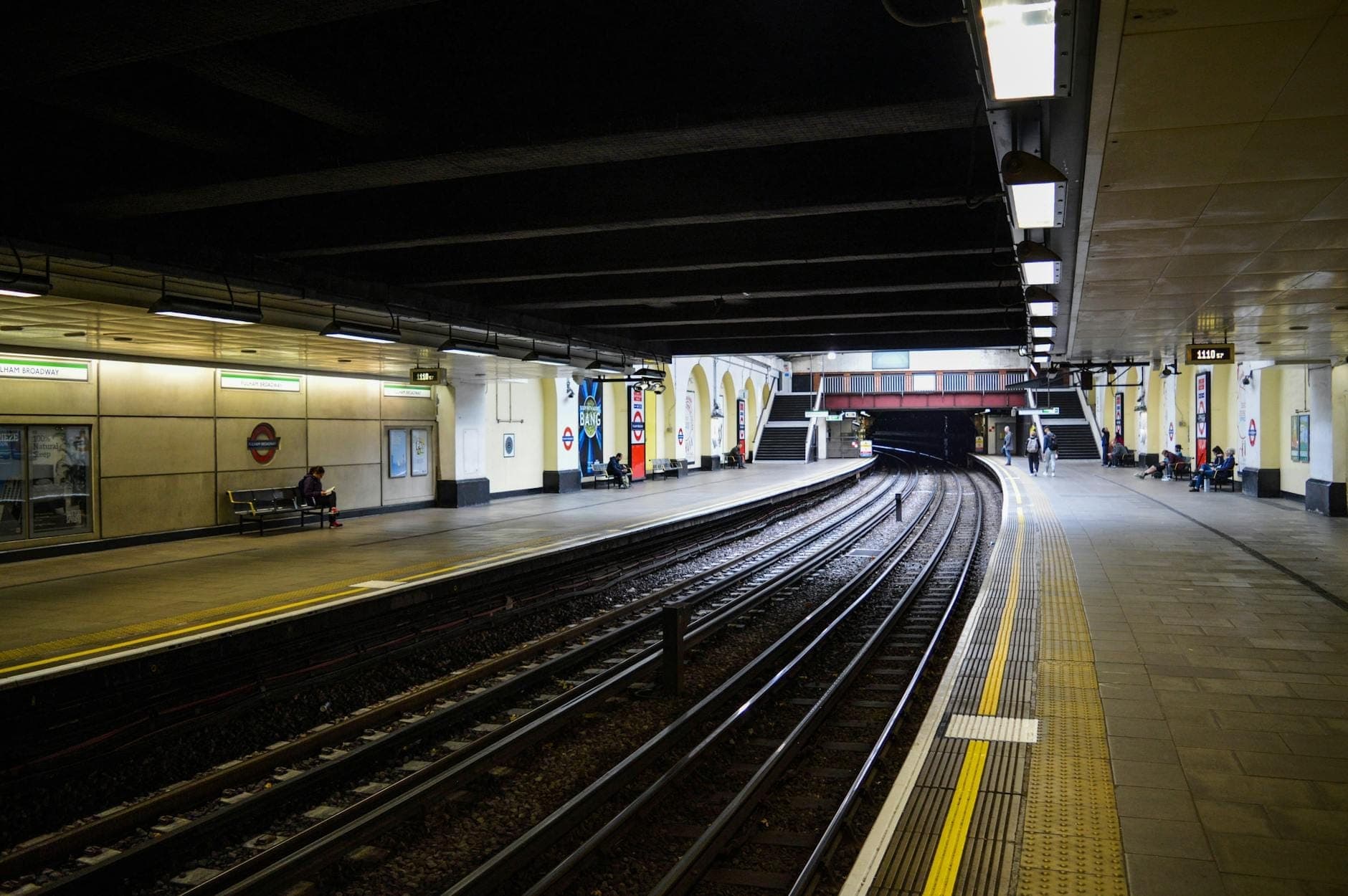 A London Underground District line platform with visible tracks and signature roundel, showing a real London transport scene.