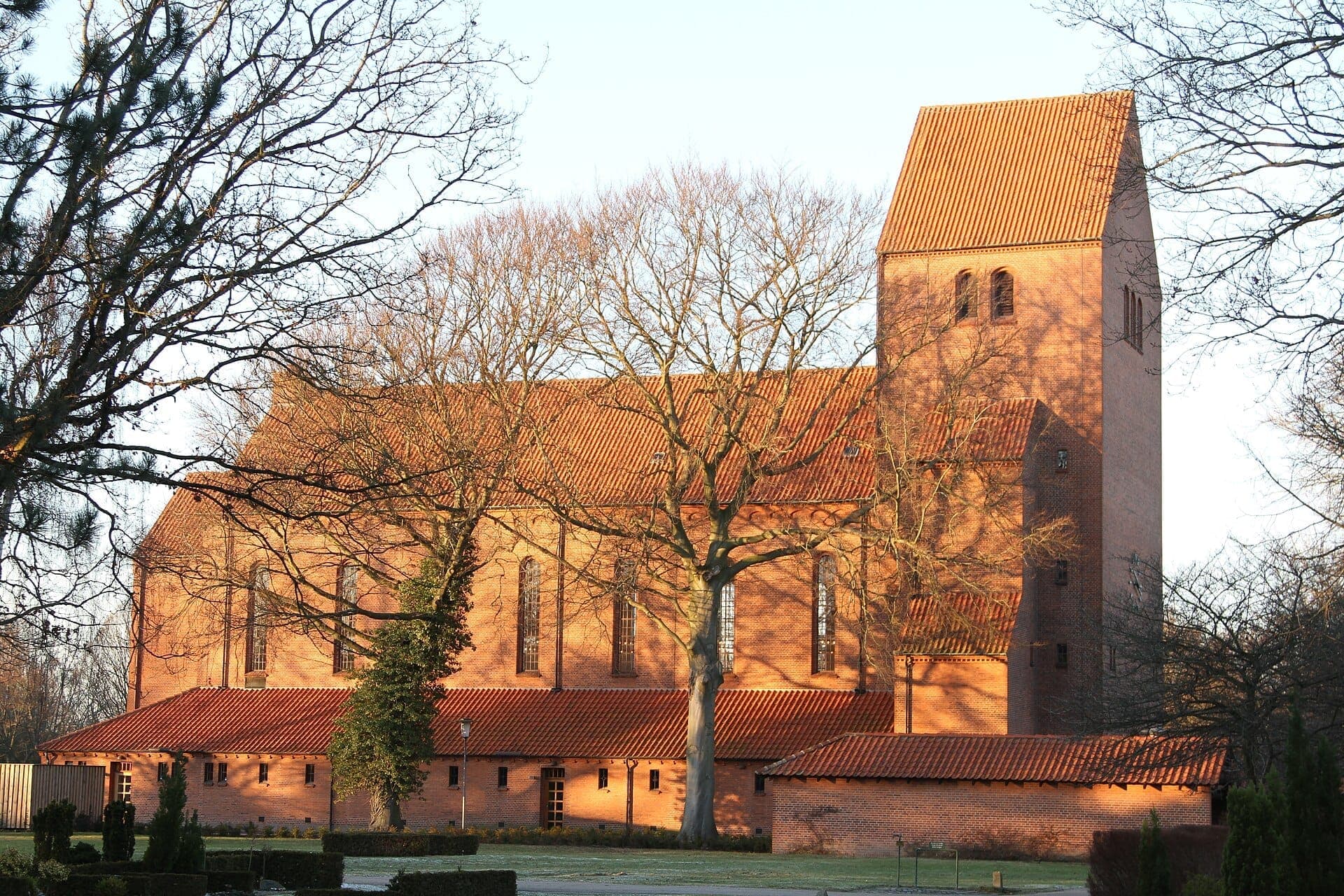 Backsteinkirche auf dem Assistens Friedhof, umgeben von blätterlosen Bäumen im sanften Nachmittagslicht, Nørrebro, Kopenhagen.