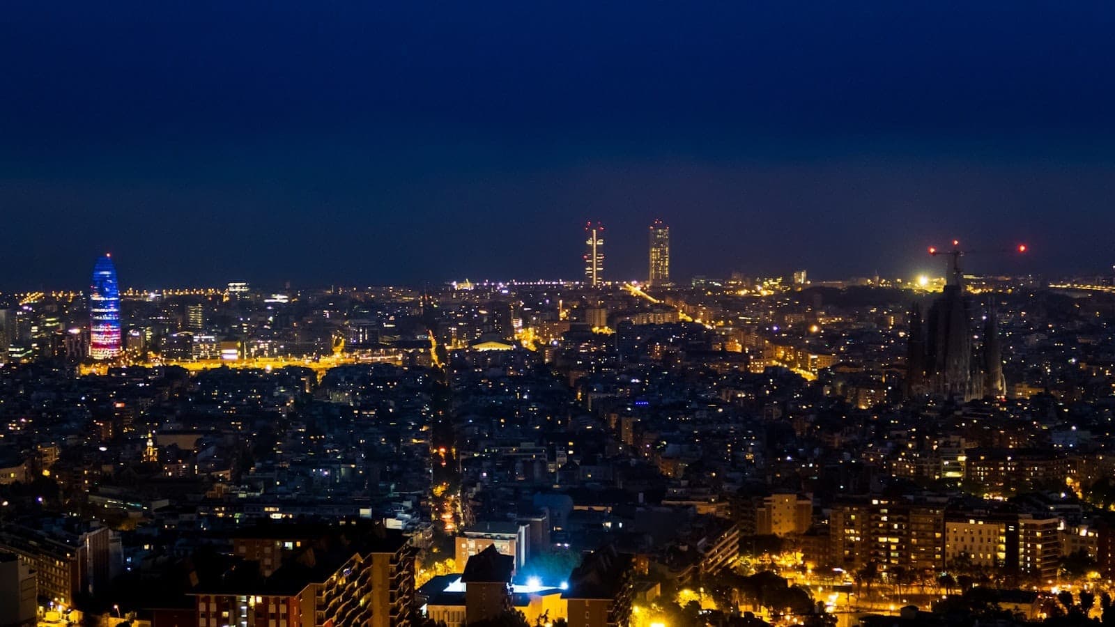 Toàn cảnh Barcelona về đêm với những tòa nhà sáng rực và bầu trời xanh thẳm, toát lên vẻ sôi động đặc trưng của thành phố sau khi hoàng hôn buông.