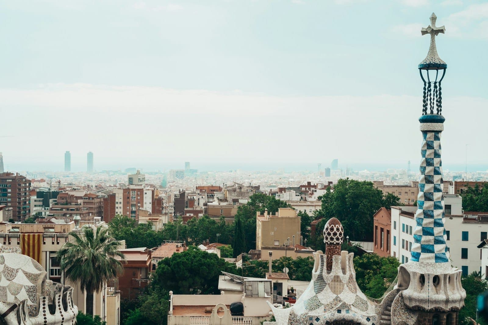 Toàn cảnh Barcelona nhìn từ Công viên Güell với những mảnh ghép khảm màu sắc của Gaudí ở phía trước và đường chân trời thành phố cùng biển xanh ở phía xa.