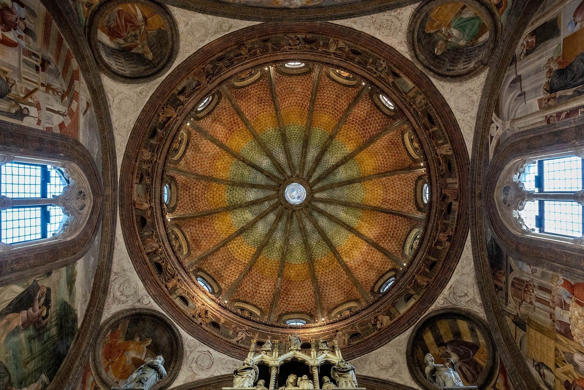 Detailed view of the vibrant Renaissance dome and frescoes inside the Basilica di Sant'Eustorgio in Milan, with natural light coming through arched windows.
