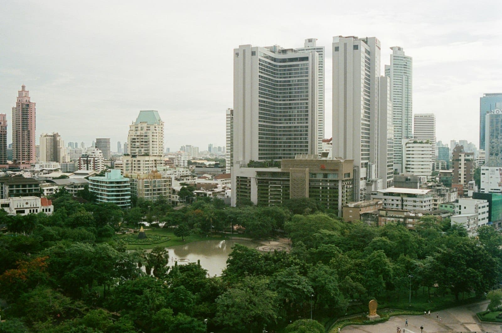 Công viên Benchasiri ở Sukhumvit với hồ nước, bãi cỏ xanh và đường chân trời Bangkok phía sau gần Phrom Phong