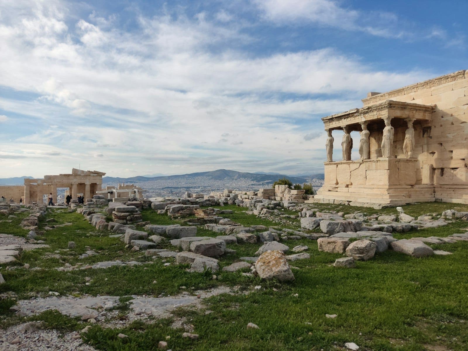 Templo ng Erechtheion na may mga pigura ng Caryatid at arkeolohikal na mga guho sa burol ng Acropolis sa ilalim ng asul na langit sa Athens, Greece.