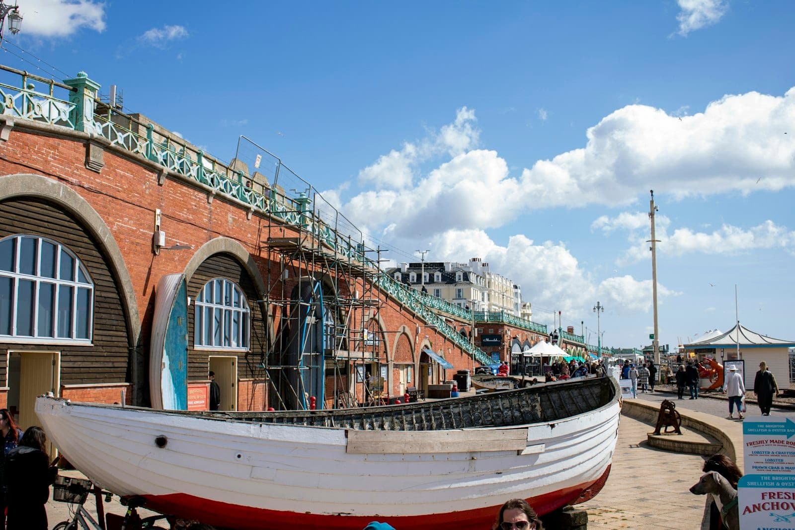Nhìn ra bờ biển Brighton với dãy mái vòm gạch xưa, trời xanh và thuyền đánh cá truyền thống gợi lên nét di sản và biển đặc trưng của Brighton.