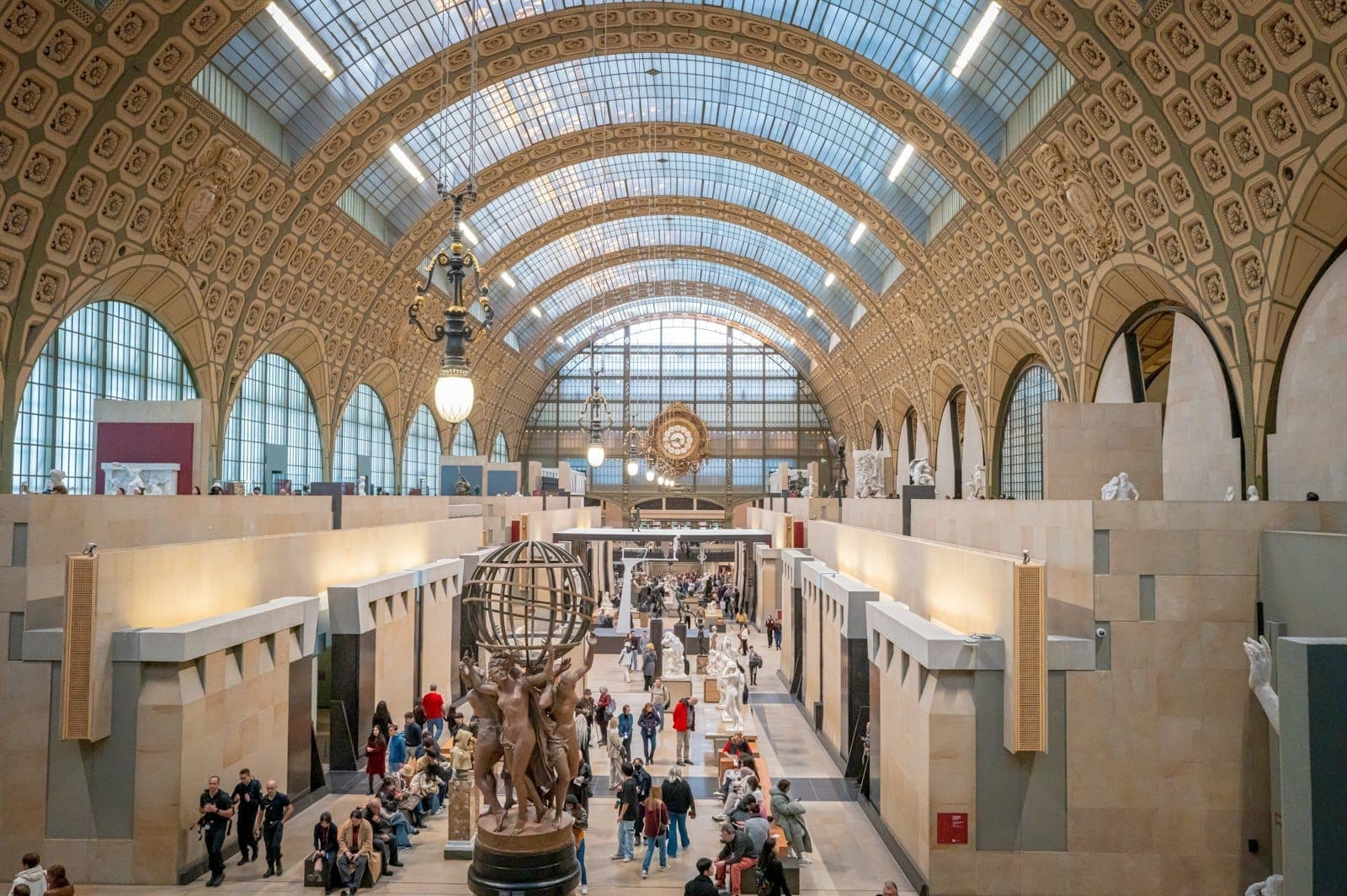 Toàn cảnh đại sảnh vòm rộng lớn của Musée d'Orsay với du khách, tác phẩm điêu khắc và ánh sáng tự nhiên xuyên qua trần kính vòm cong.