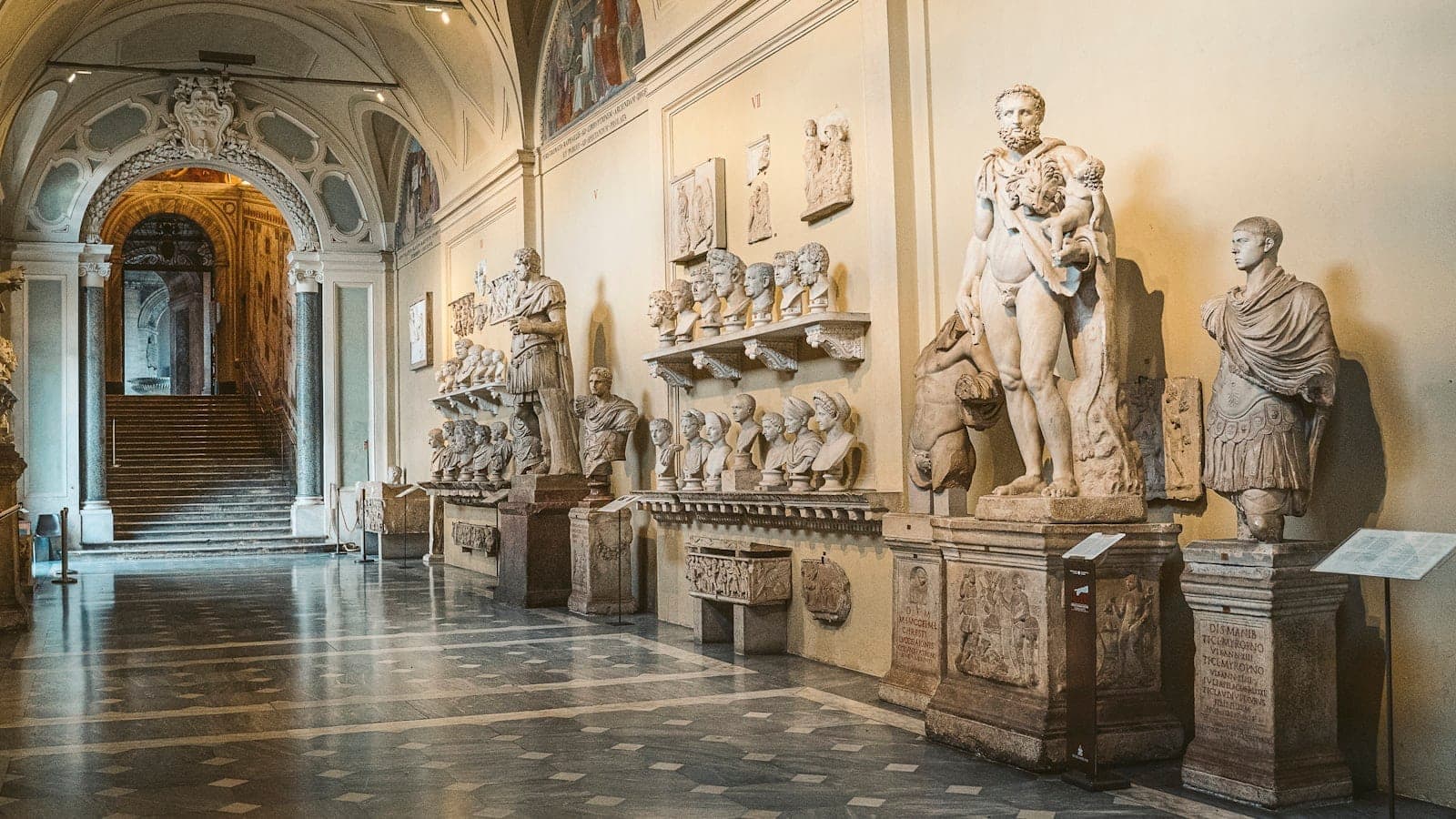 Toàn cảnh đại sảnh hoành tráng trong một bảo tàng ở Rome, với các bức tượng và tượng bán thân La Mã trưng bày dọc theo tường dưới mái vòm, gợi lên không khí nghệ thuật và lịch sử.