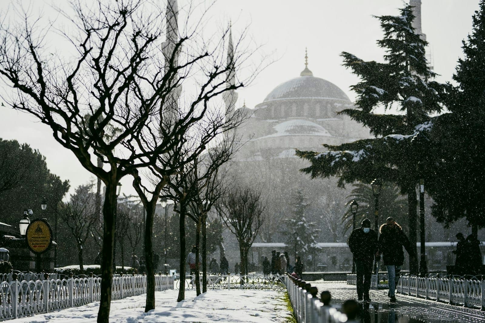 Menschen, die an schneebedeckten Bäumen vorbei zur Hagia Sophia in Istanbul an einem Wintertag spazieren.
