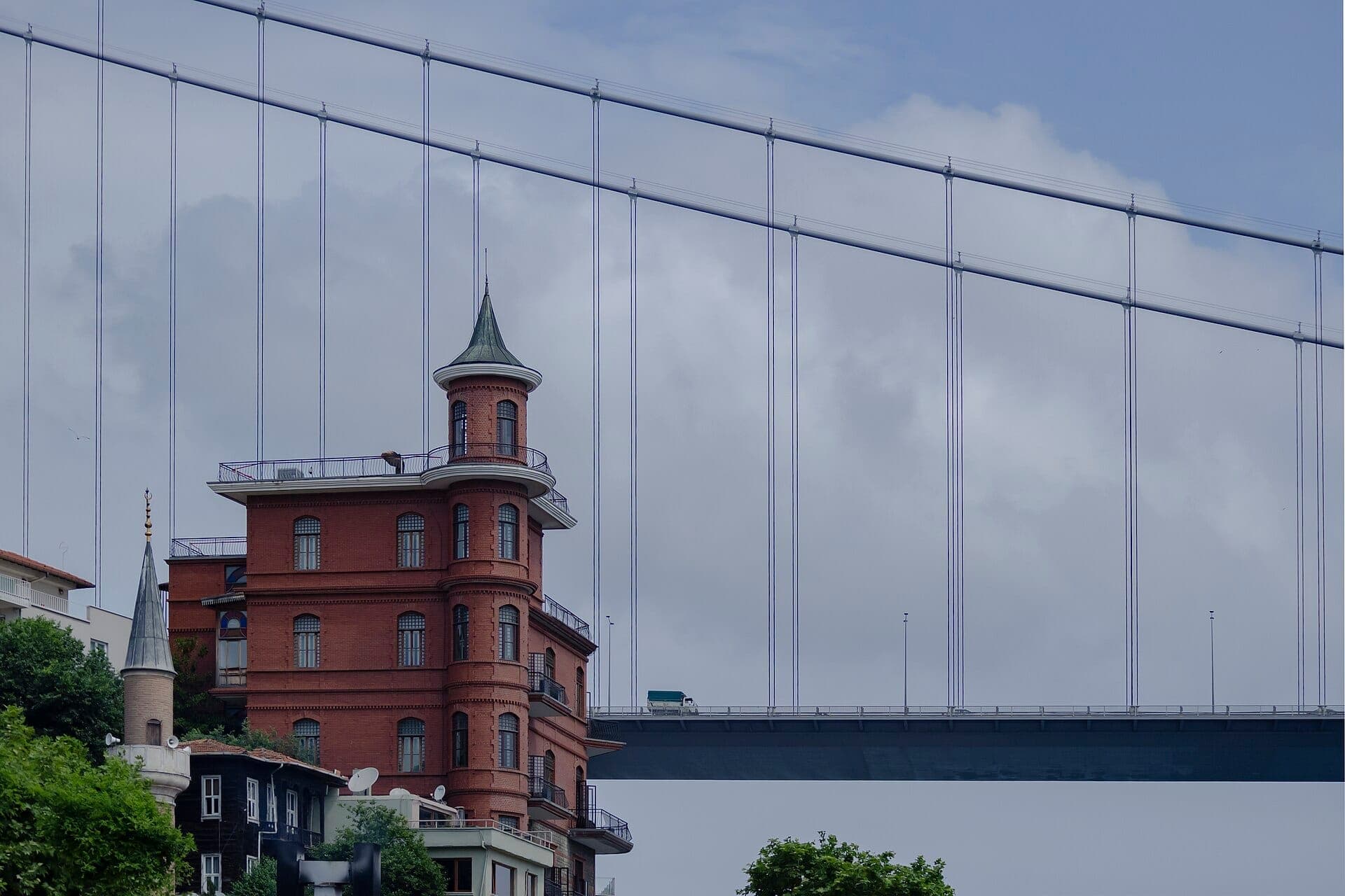 Das historische rotziegel Perili Köşk, Heimat des Borusan Contemporary, steht unter der Bosporus-Brücke vor einem bewölkten Istanbuler Himmel.