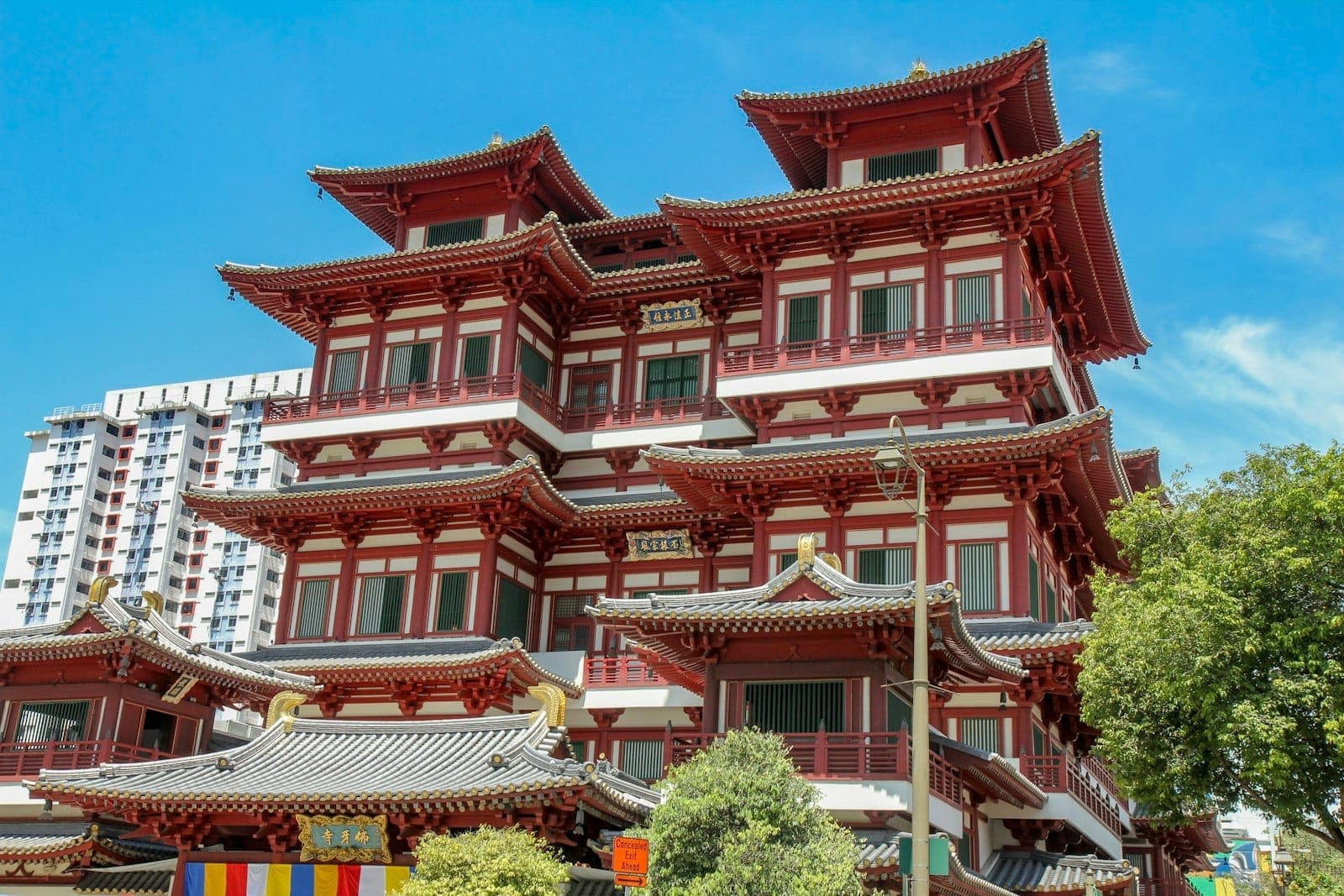 The exterior of the Buddha Tooth Relic Temple in Singapore under a blue sky, showcasing its ornate Tang Dynasty architectural style and red and white facade.