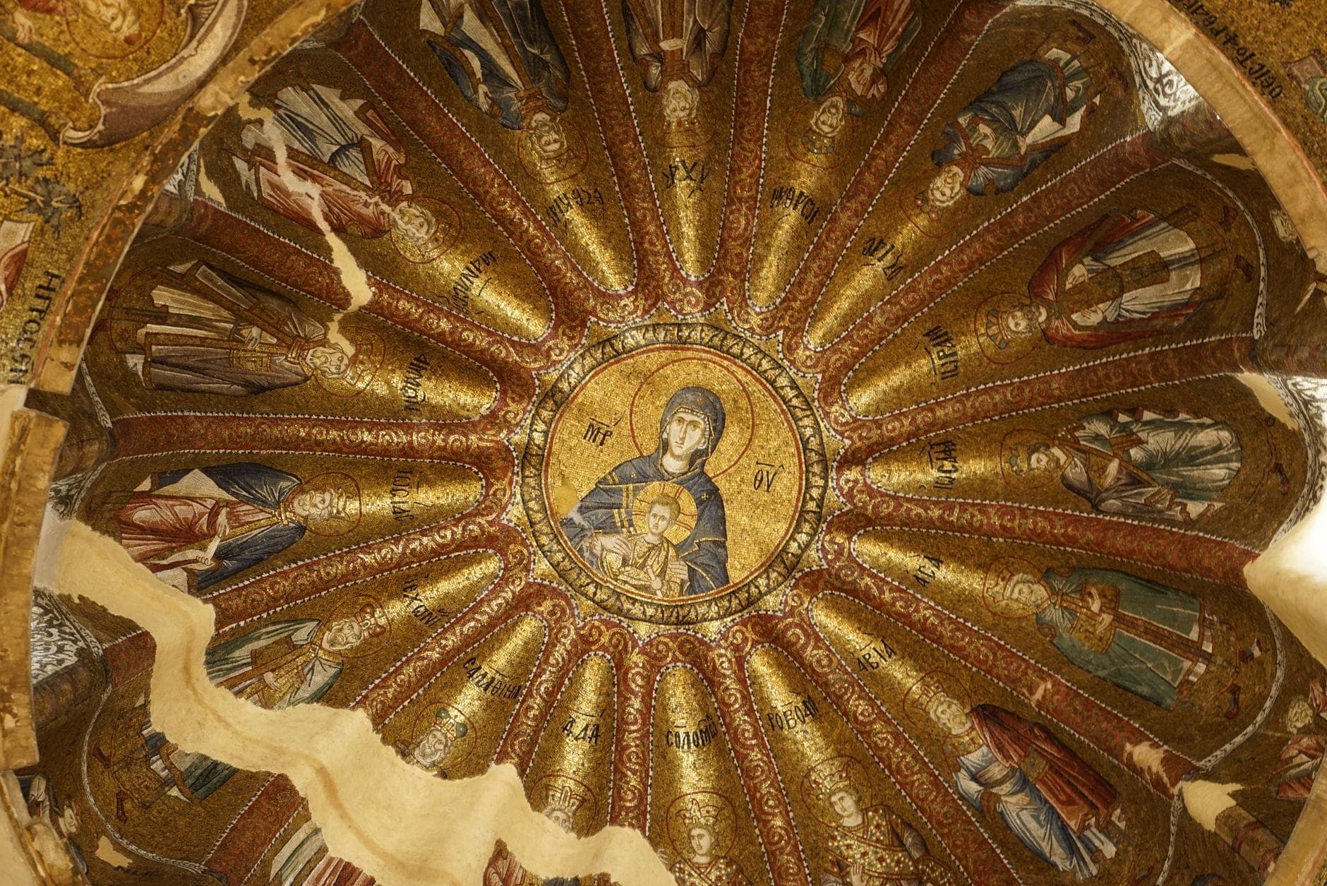 Golden Byzantine dome mosaic featuring the Virgin Mary and Child surrounded by saints, exemplifying intricate Christian art within a church interior.