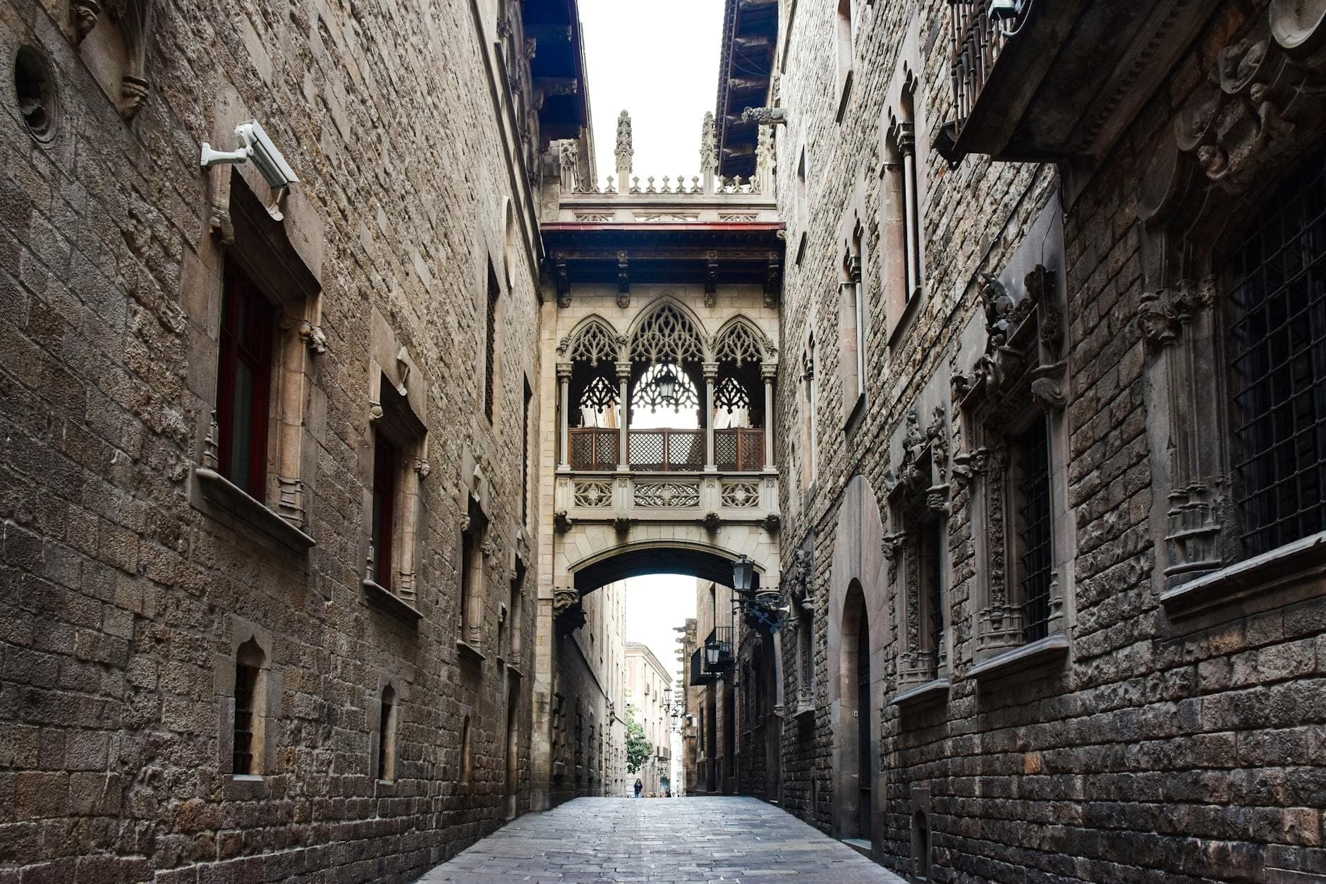 Cảnh nhìn dọc theo Carrer del Bisbe ở Barcelona, nổi bật với cây cầu có mái che tân Gothic Pont del Bisbe bắc ngang giữa hai tòa nhà đá cổ trong Khu Gothic.