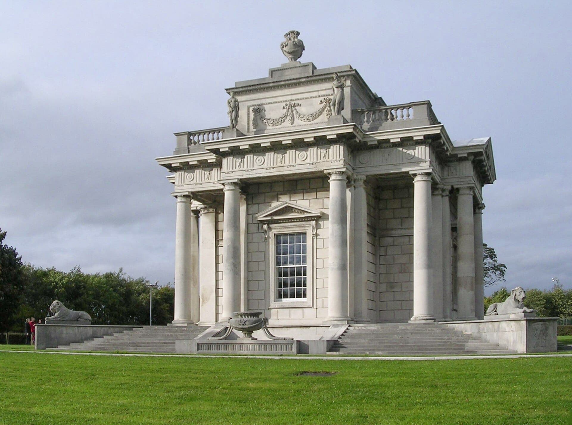 Il Casino Marino a Dublino, un piccolo edificio neoclassico con alte colonne e leoni di pietra, si erge su prati verdi curati sotto un cielo nuvoloso.