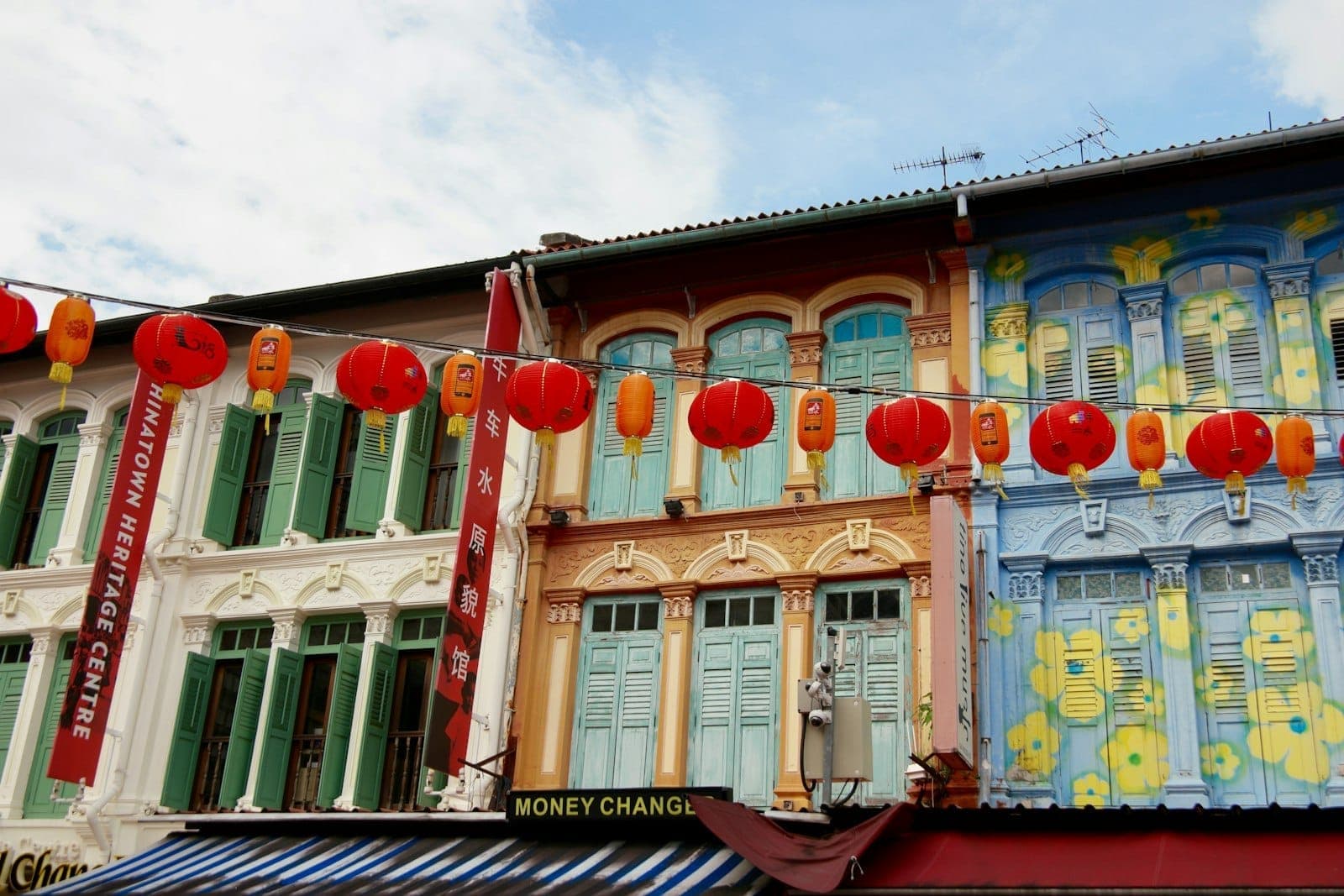 Colorful shophouses on Pagoda Street in Singapore’s Chinatown, adorned with red lanterns. The Chinatown Heritage Centre signage is visible among the restored historic buildings.