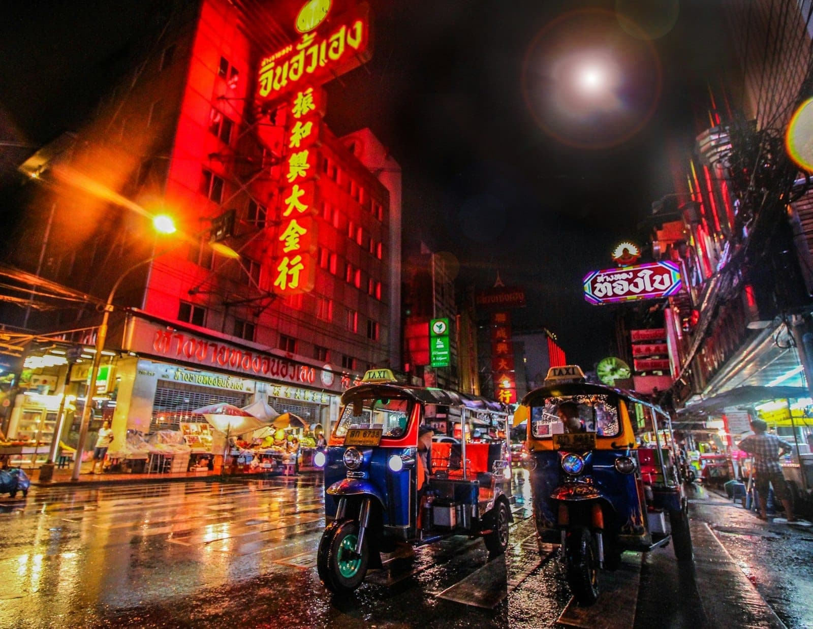 Mga tuk-tuk sa Yaowarat Road sa Bangkok Chinatown sa gabi na may mga neon na karatulang Tsino
