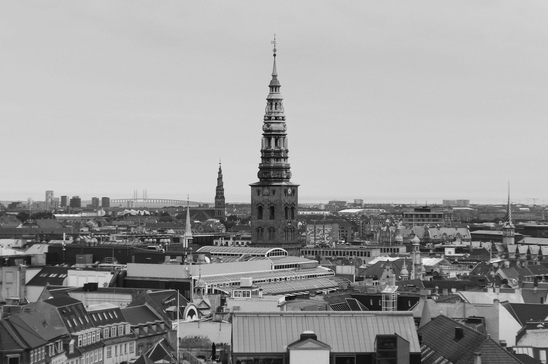 Schwarz-weißes Stadtpanorama von Kopenhagen mit dem markanten Spiralturm der Erlöserkirche, der hoch über den Dächern aufragt und die Skyline dominiert.