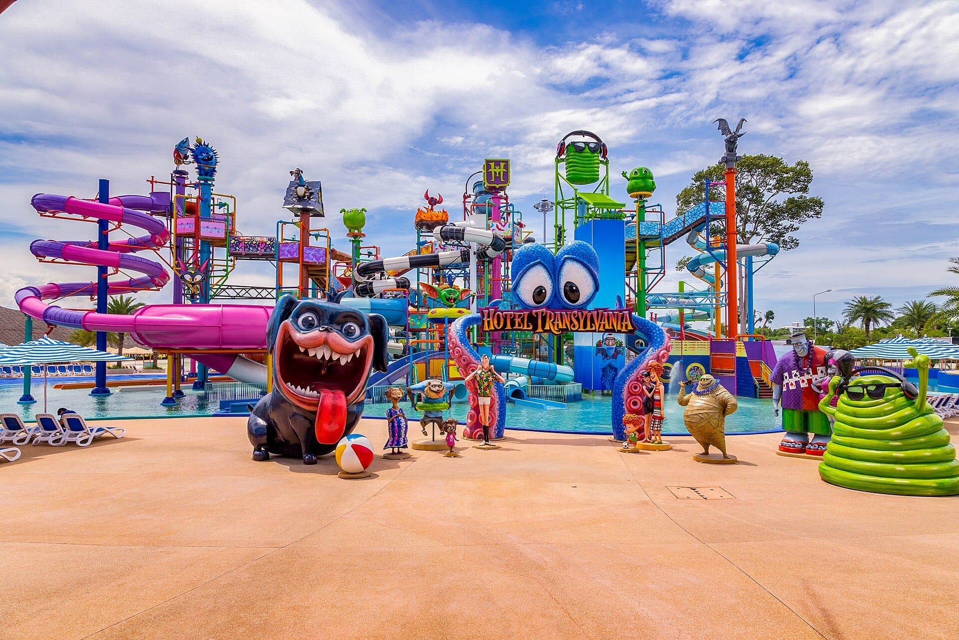 Colorful water slides, playful cartoon characters, and a Hotel Transylvania sign at Columbia Pictures Aquaverse water park under a partly cloudy sky.