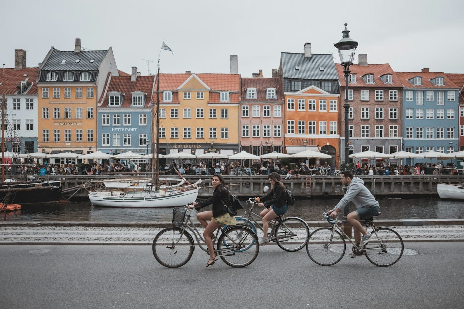 Ludzie jeżdżący na rowerach przed kolorowymi budynkami wzdłuż nabrzeża Nyhavn w Kopenhadze.