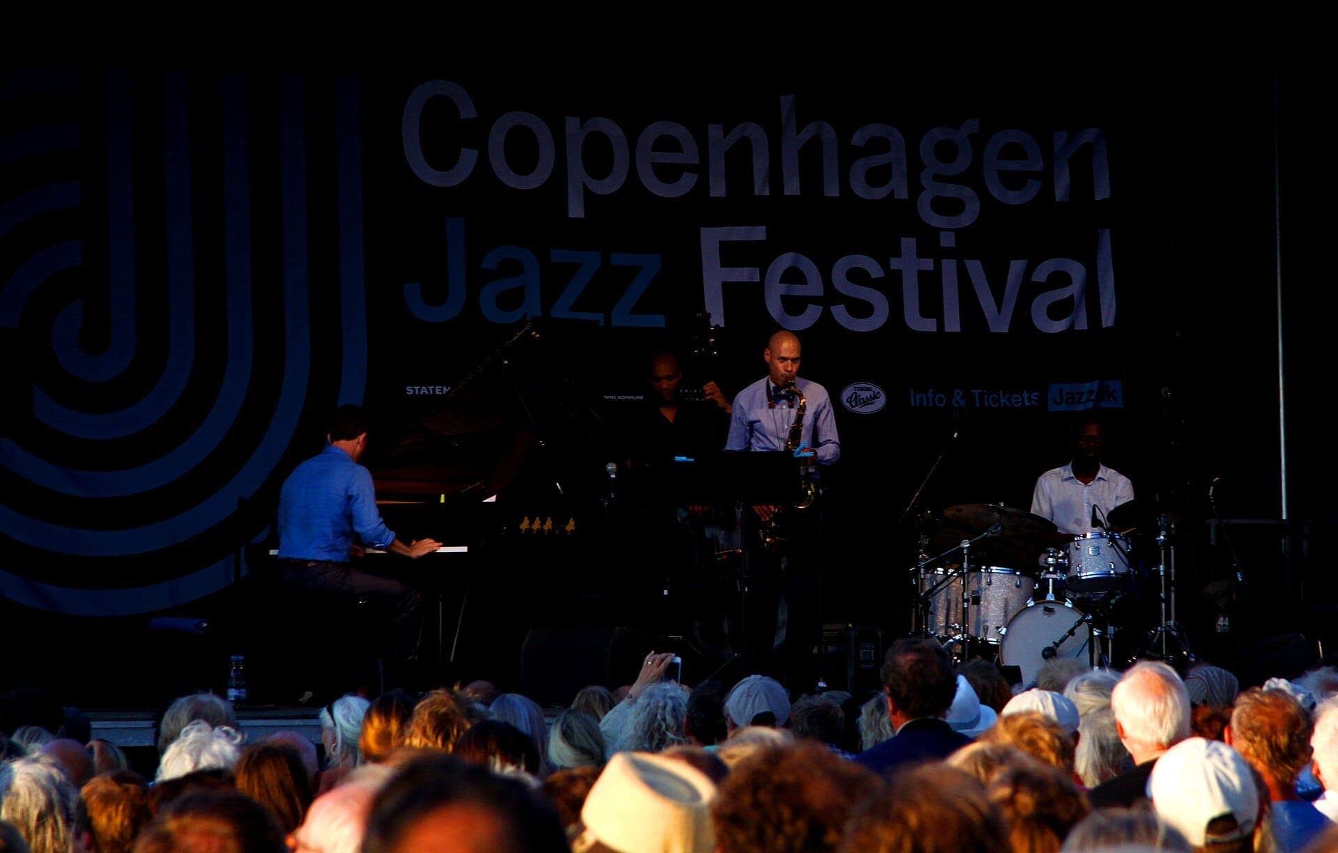 Jazzband auf der Bühne beim Copenhagen Jazz Festival, mit Publikum unter Abendlichtern und dem Veranstaltungsbanner im Hintergrund.