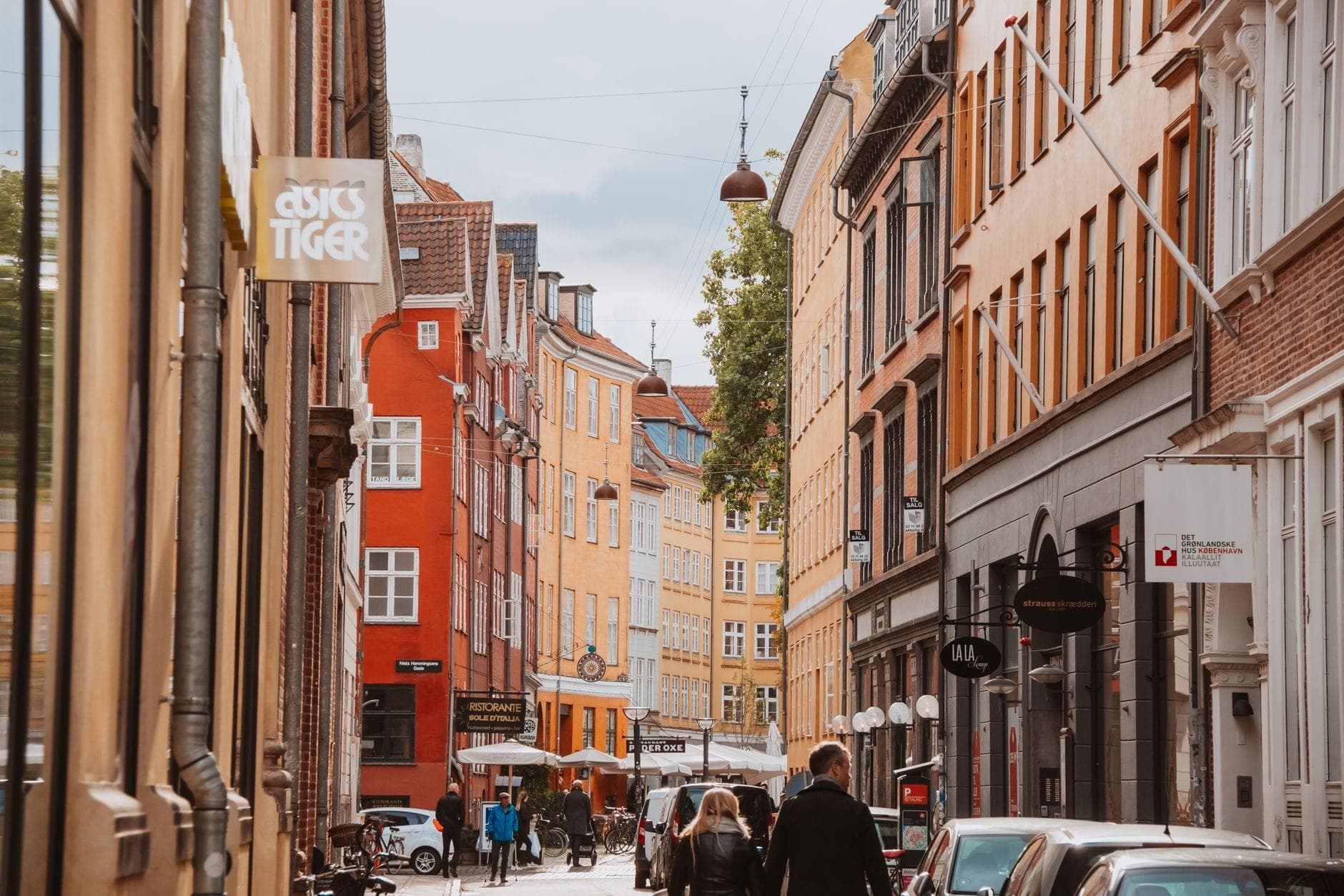 Con phố thân thiện với người đi bộ đầy quyến rũ ở Copenhagen với những tòa nhà đầy màu sắc, người đi dạo và bầu không khí đô thị sôi động dưới bầu trời có mây rải rác.