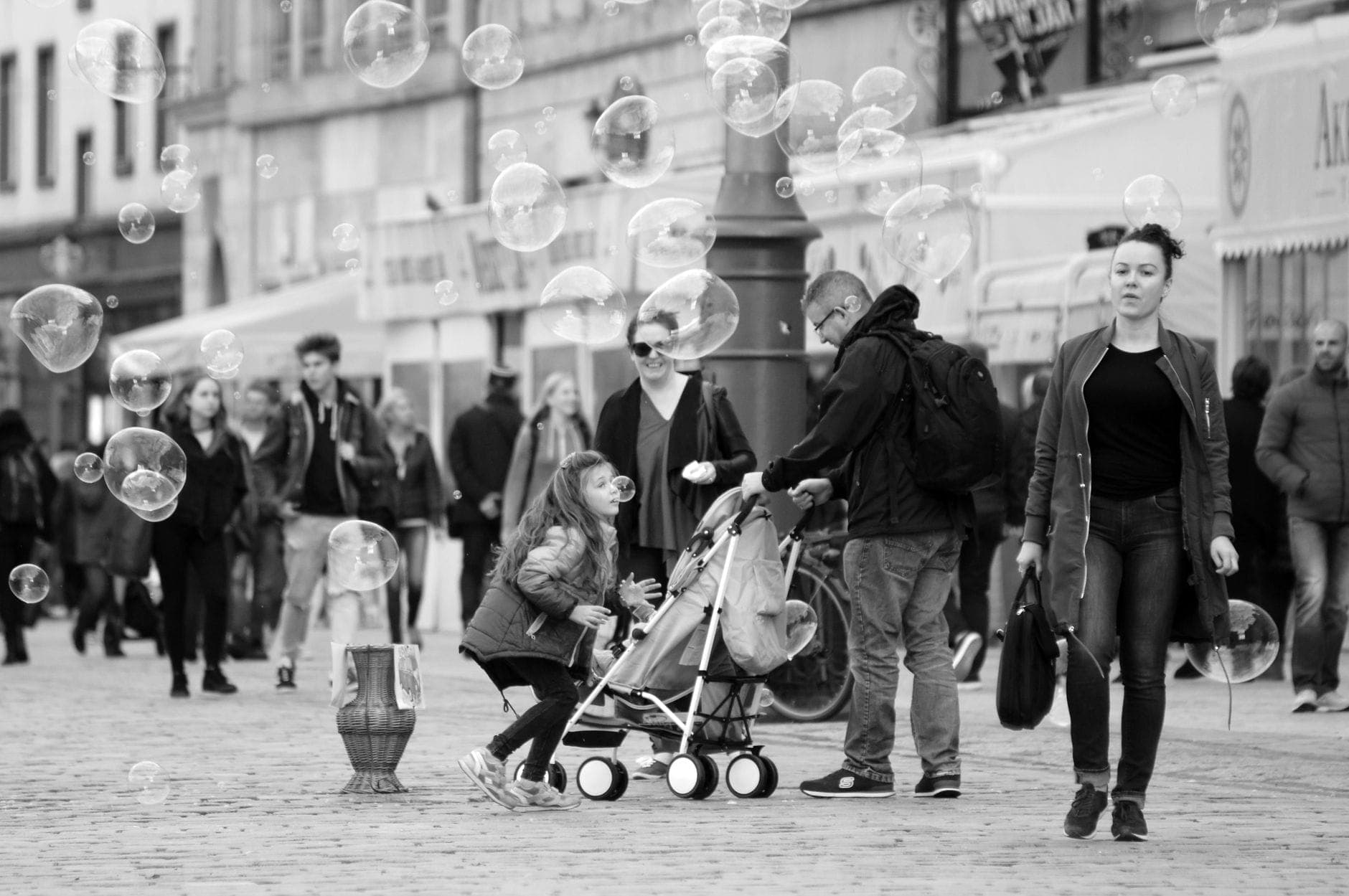 Belebte Stadtstraße mit Familien, einem Mann, der einen Kinderwagen schiebt, Kindern und Fußgängern, die eine urbane Familienreiseumgebung zeigt.