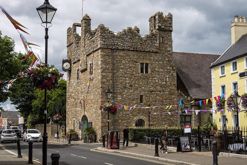 Dalkey Castle & Heritage Centre in Dublin, ein mittelalterlicher Steinturm mit Zinnen, bunten Wimpeln und farbenfrohen Gebäuden in einer belebten Straße.
