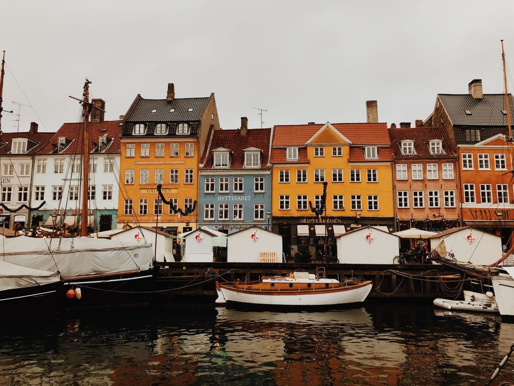 Case storiche colorate e barche lungo il celebre lungofiume di Nyhavn a Copenaghen in una giornata nuvolosa.
