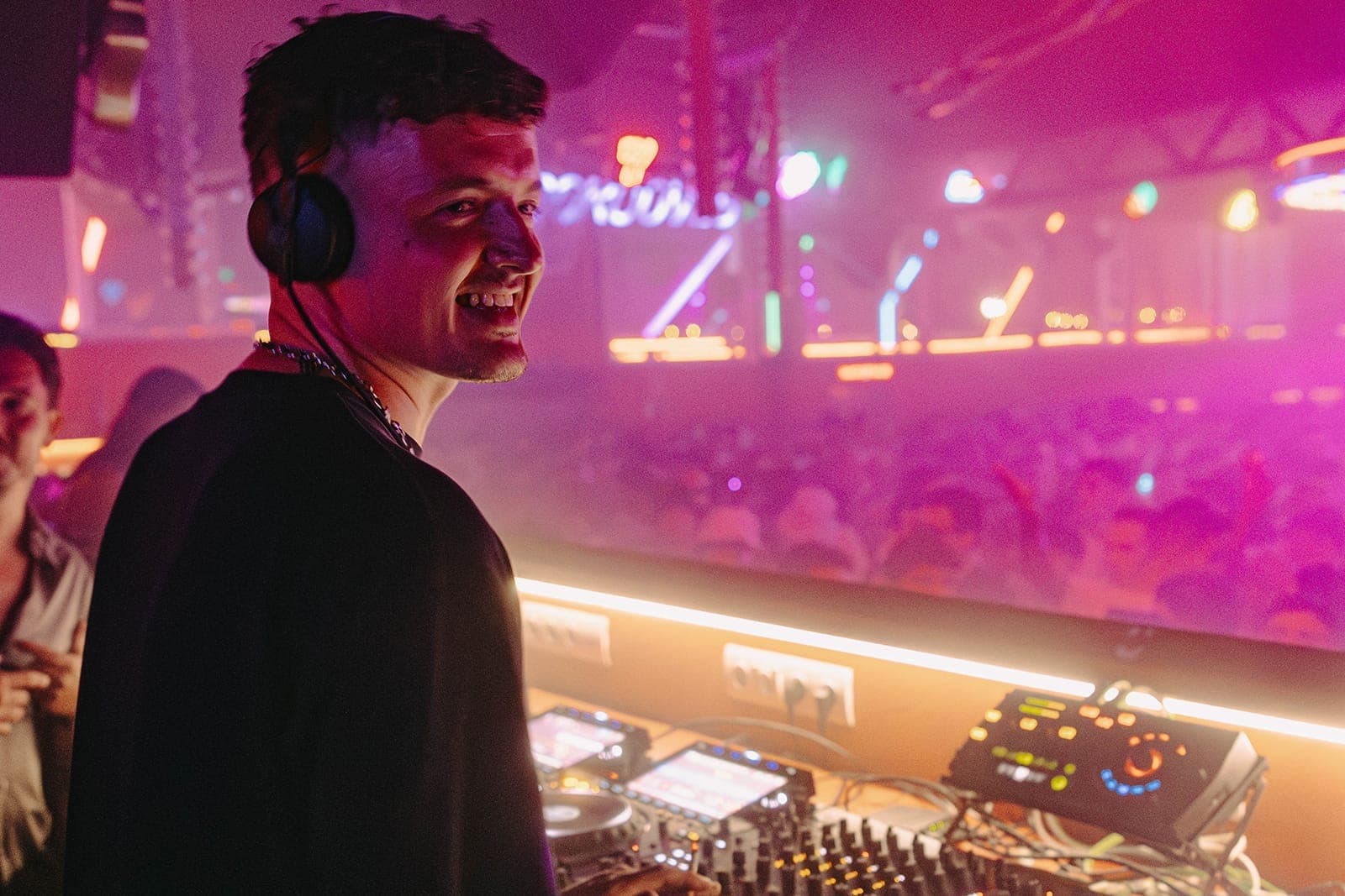 DJ performing at DC10 Ibiza with a crowd dancing under colorful neon lights and hazy club atmosphere in the background.