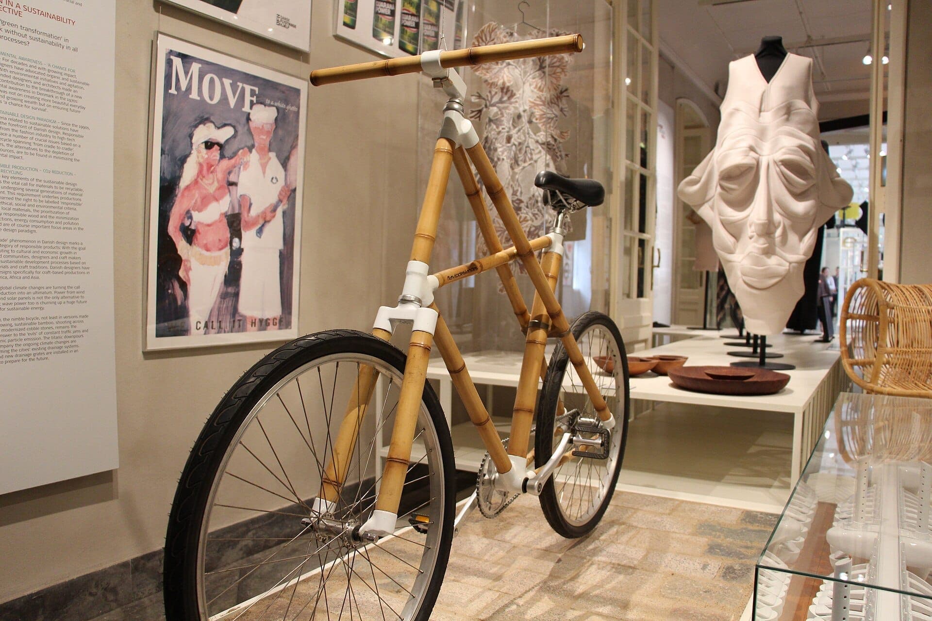 Ein Bambus-Fahrrad wird neben modernen Kunst- und Designobjekten im Designmuseum Danmark in Kopenhagen ausgestellt, mit weichem Innenlicht und detailreichen Interieurs.