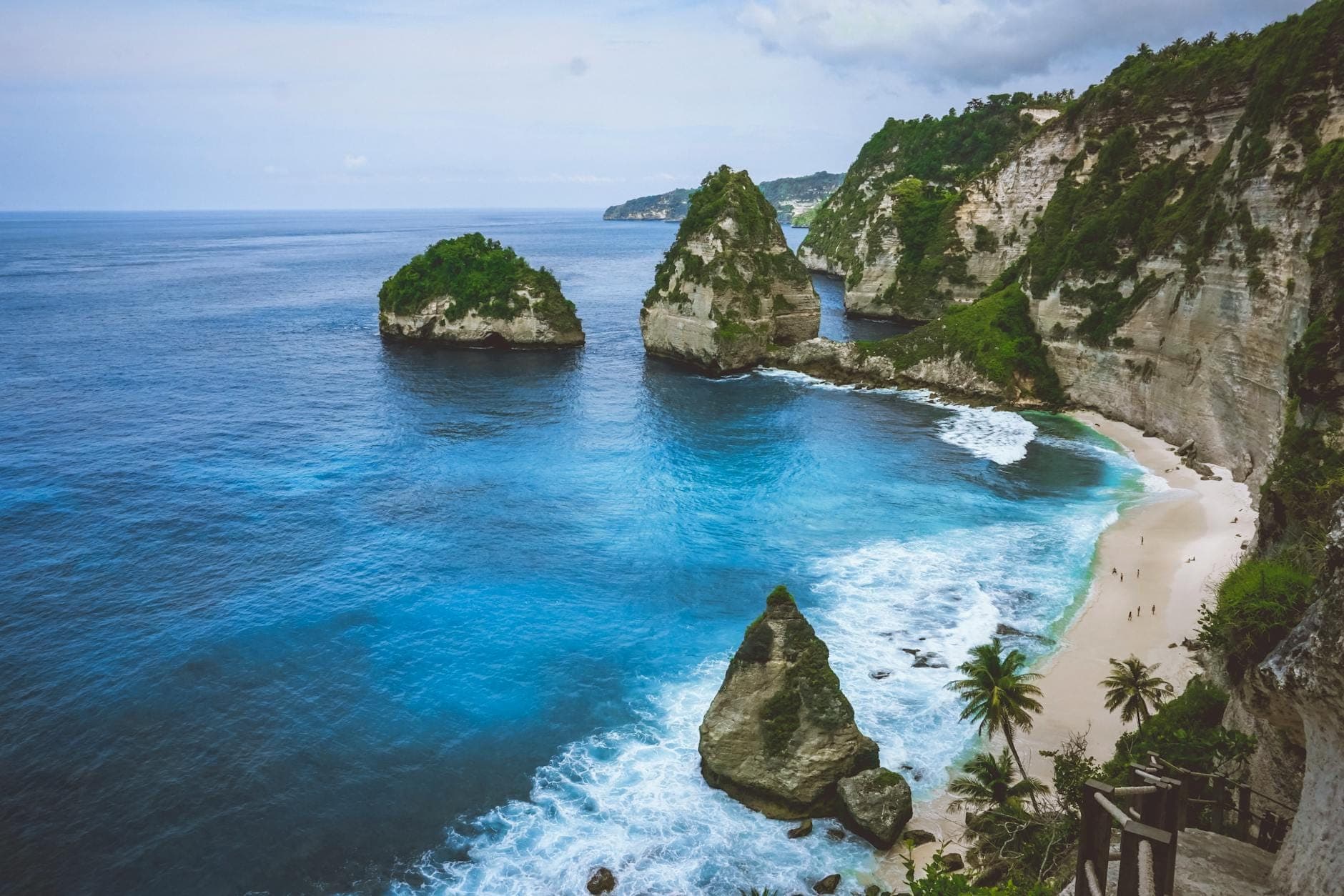 Cát trắng và nước xanh ngọc tại Diamond Beach ở Nusa Penida, Bali với các trụ đá vôi vươn cao từ bờ biển