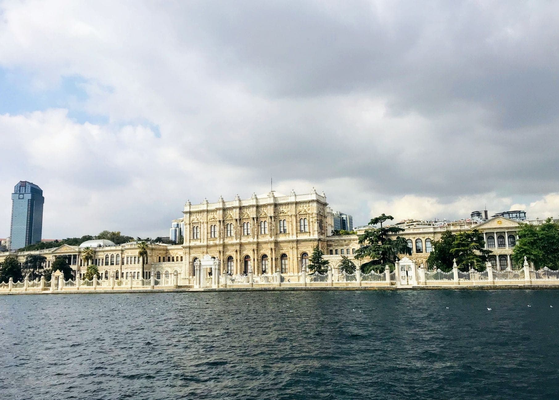 Weitwinkelpanorama der Bosporus-Fassade des Dolmabahçe-Palastes, eingerahmt von bewölktem Himmel und schimmerndem Wasser – die Dimensionen und Lage des Palastes kommen dabei eindrucksvoll zur Geltung.