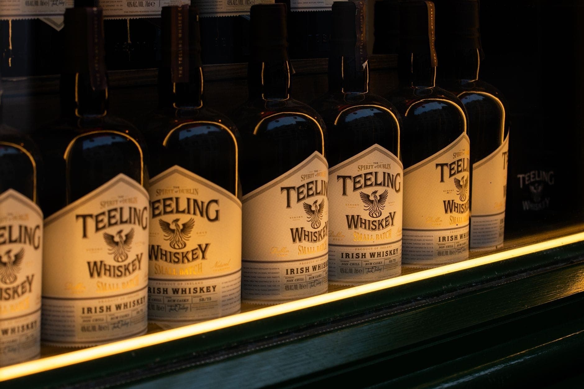 Fila di bottiglie di Teeling Irish Whiskey esposte su uno scaffale in un bar o distilleria con scarsa illuminazione.