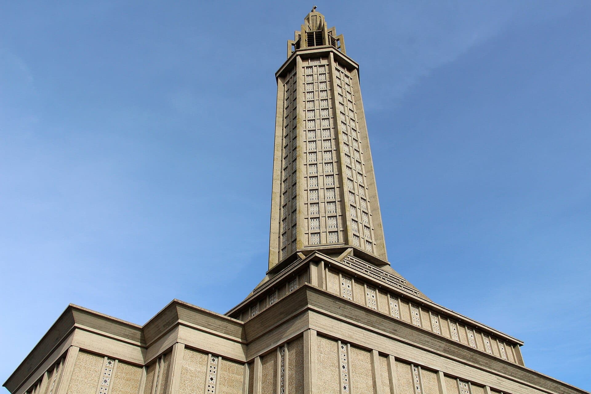 Tháp đèn sừng sững của Église Saint-Joseph tại Le Havre vươn lên trên bầu trời xanh trong, thể hiện kiến trúc bê tông hiện đại.
