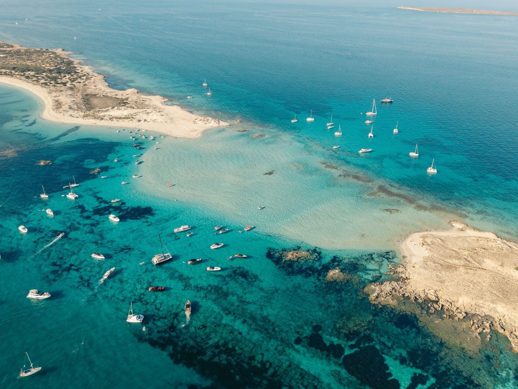 Aerial view of Formentera’s turquoise waters, sandy beaches, and many anchored boats under a clear sky, perfectly capturing the island’s coastal beauty.