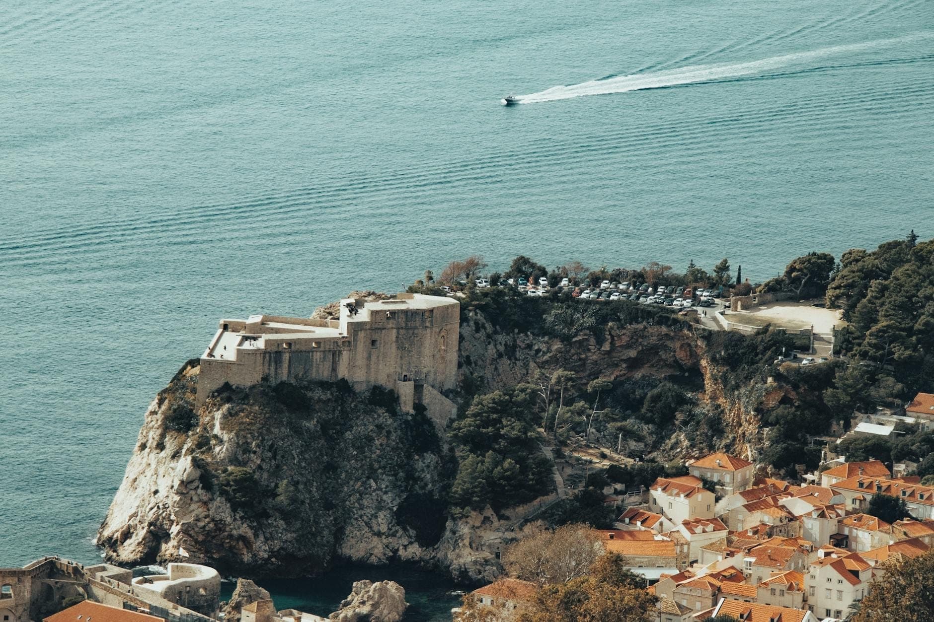 Toàn cảnh Pháo đài Imperial trên đỉnh đồi nhìn xuống phố cổ Dubrovnik và biển Adriatic, với con đường ngoằn ngoèo và bờ biển hùng vĩ.