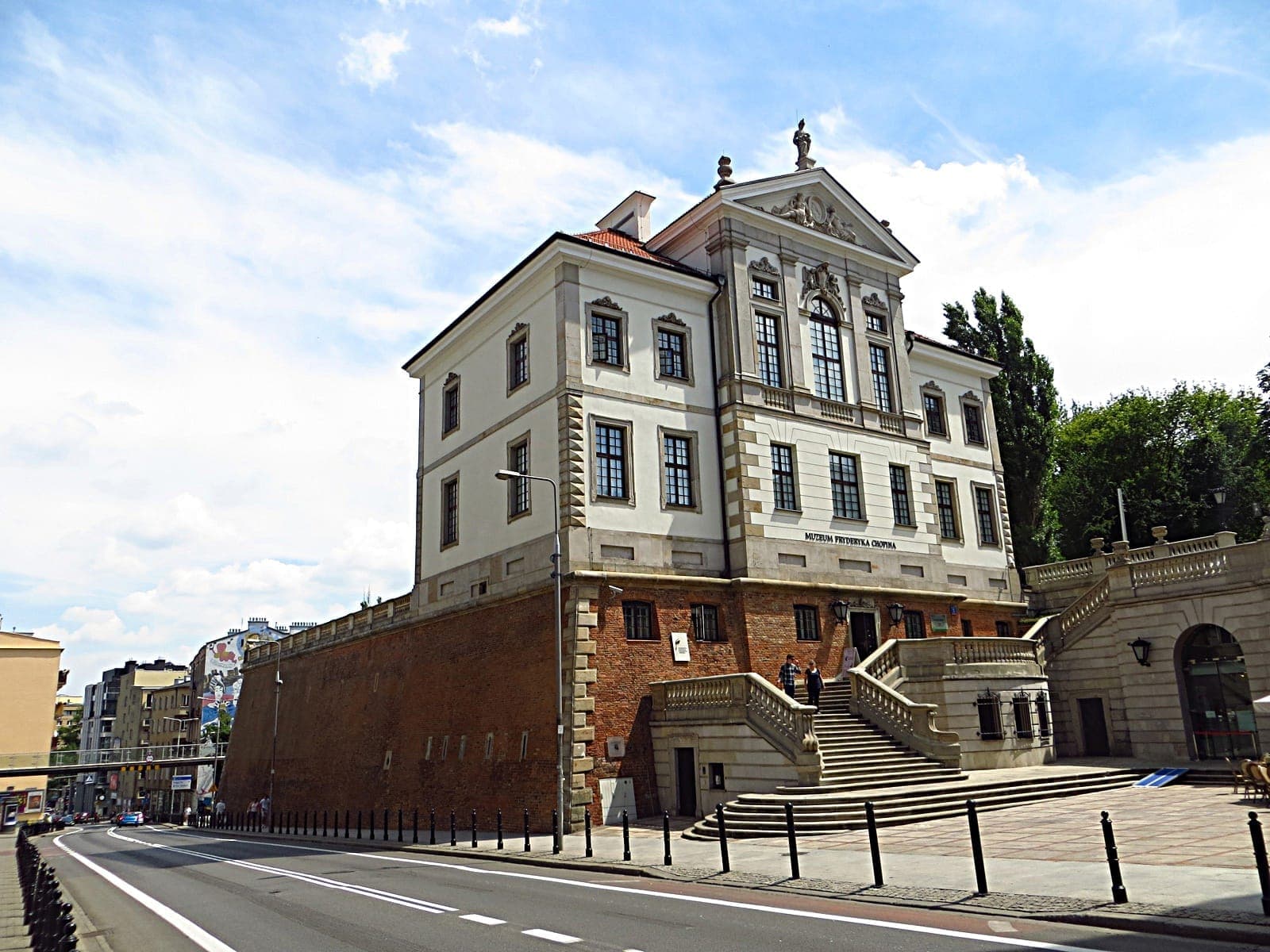 Das Gebäude des Fryderyk-Chopin-Museums in Warschau, ein stattlicher weiß-roter Backsteinpalast mit breiter Freitreppe und klassischen architektonischen Details unter blauem Himmel.