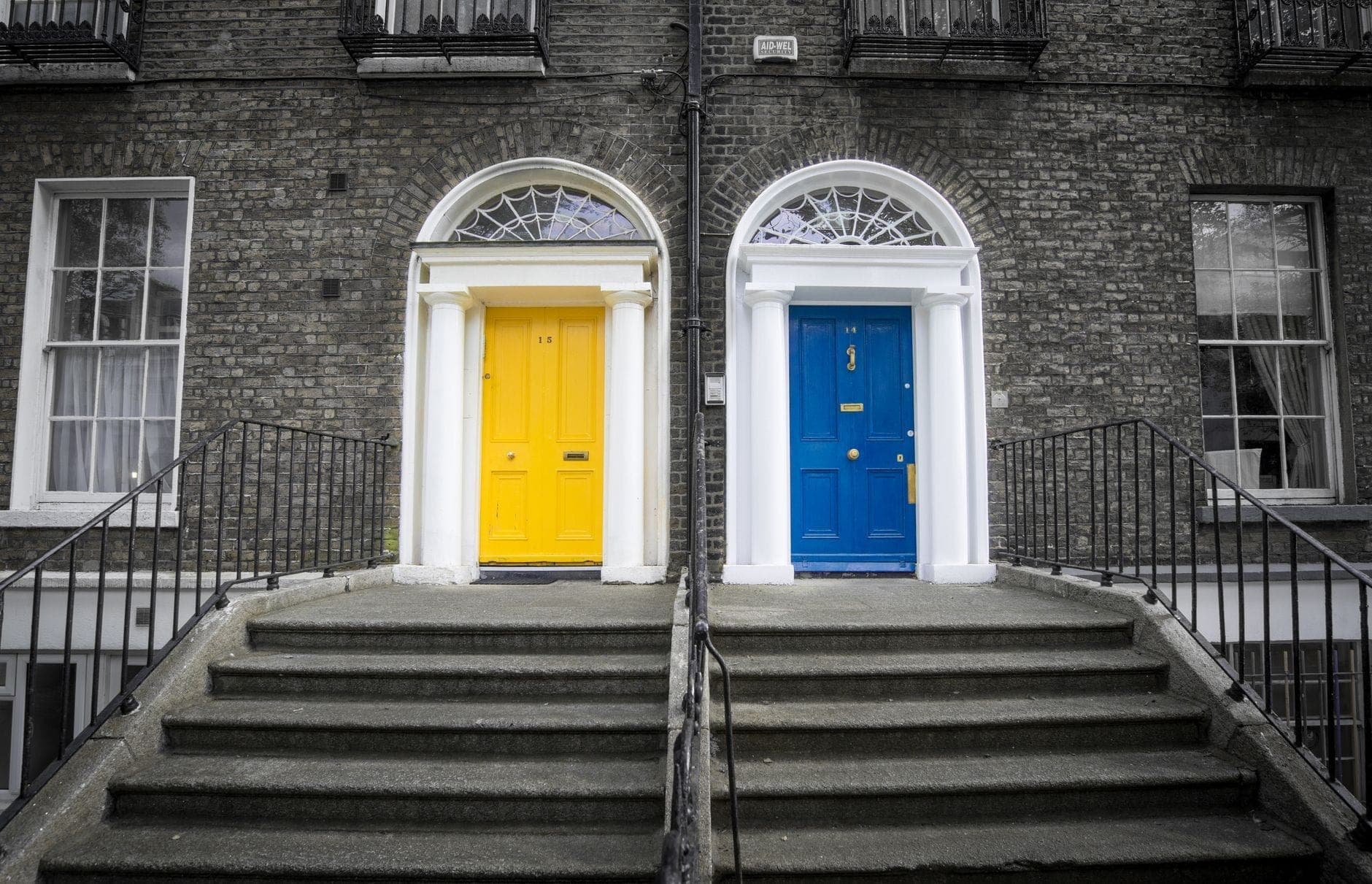 Zwei klassische georgianische Stadthauseingänge in Dublin mit leuchtend gelben und blauen Türen, Fächerfenstern und Backsteinmauerwerk – markante Merkmale georgianischer Architektur.