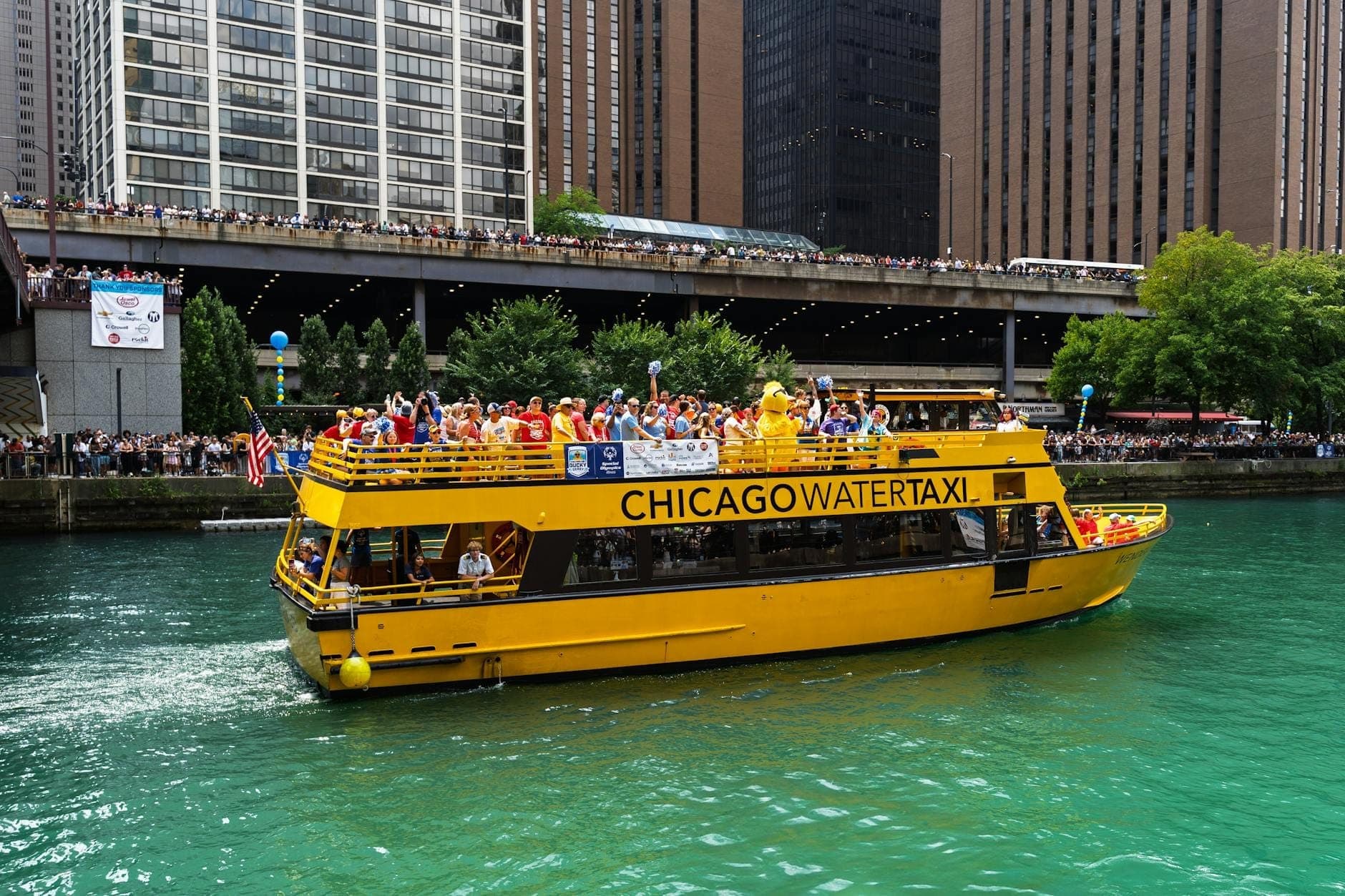 Chicago Water Taxi voller Passagiere auf dem Chicago River, umgeben von hohen Gebäuden der Innenstadt.