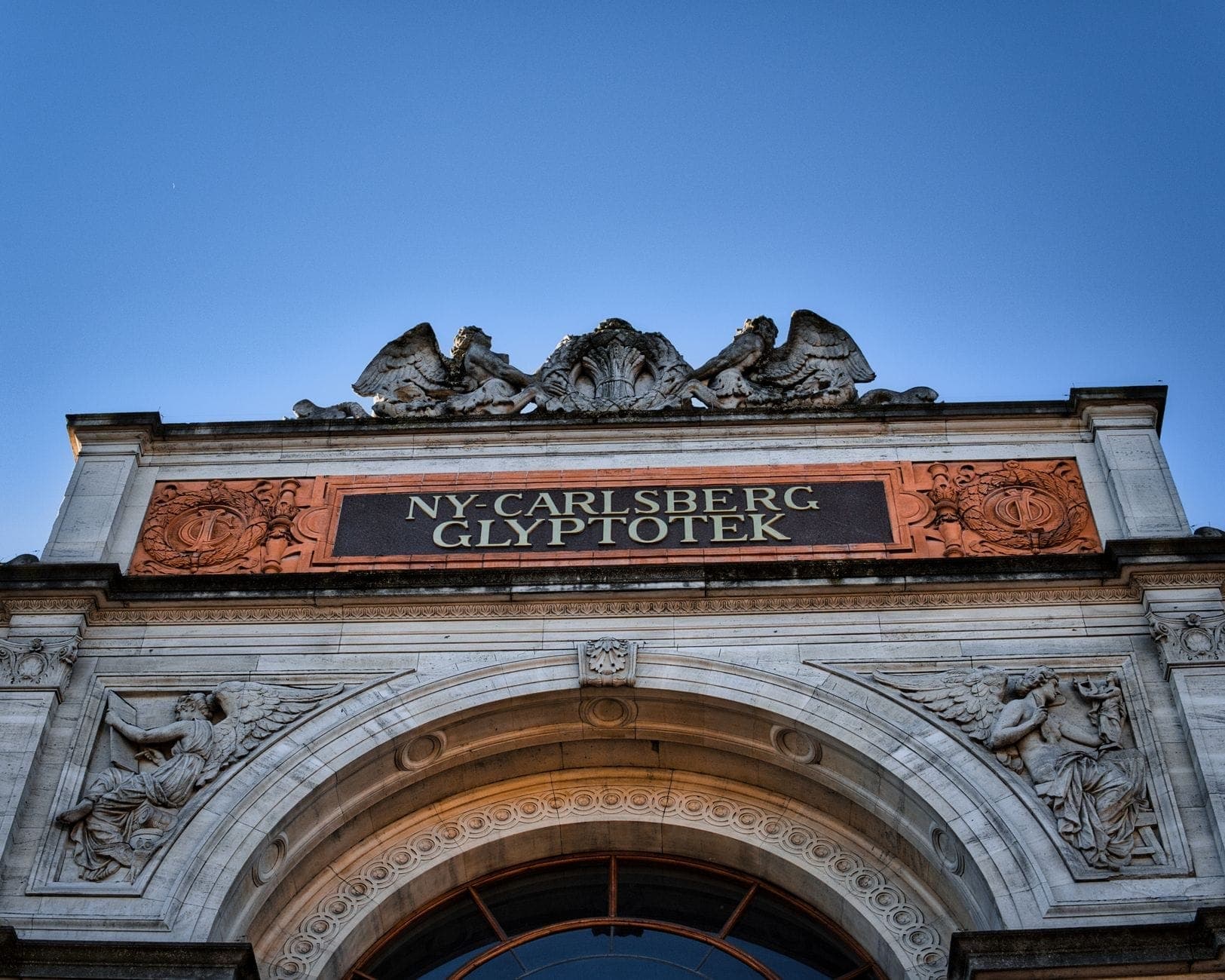 Fasada Ny Carlsberg Glyptotek, renomowanego muzeum sztuki w Kopenhadze, pod bezchmurnym błękitnym niebem