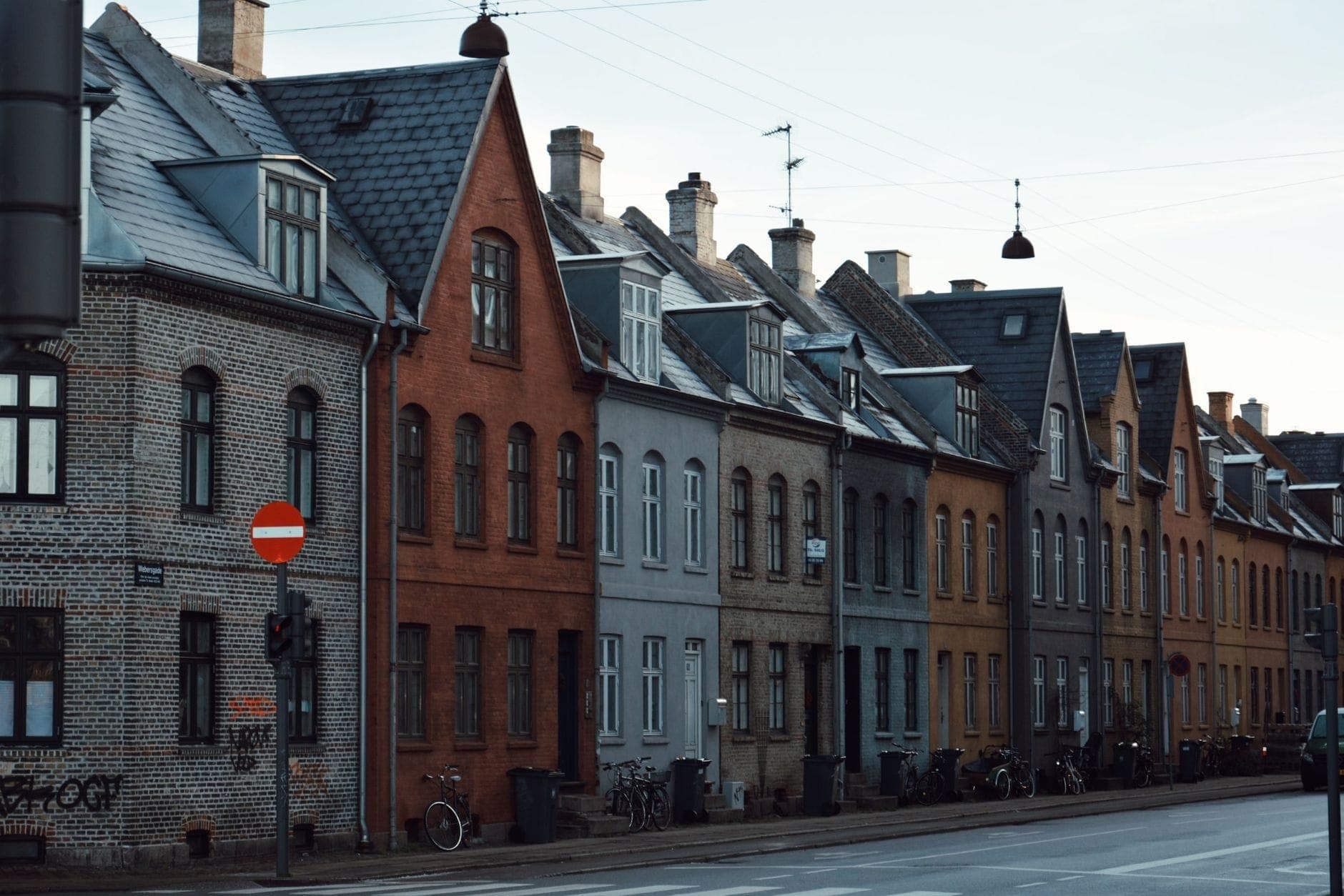 Rząd uroczych, kolorowych budynków mieszkalnych i zaparkowanych rowerów wzdłuż spokojnej ulicy w dzielnicy Copenhagen.