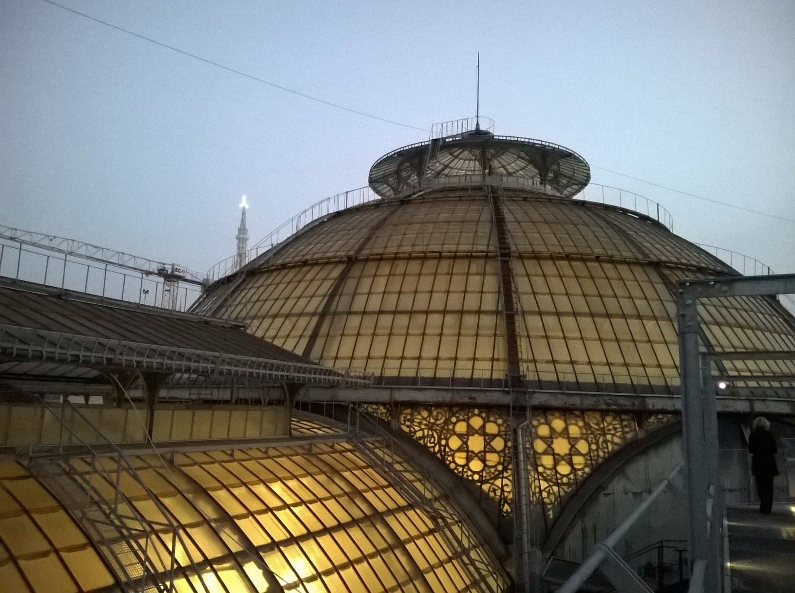 The domed glass rooftop of the Galleria Vittorio Emanuele II at dusk, seen from the Highline Galleria walkway, with subtle city lights.