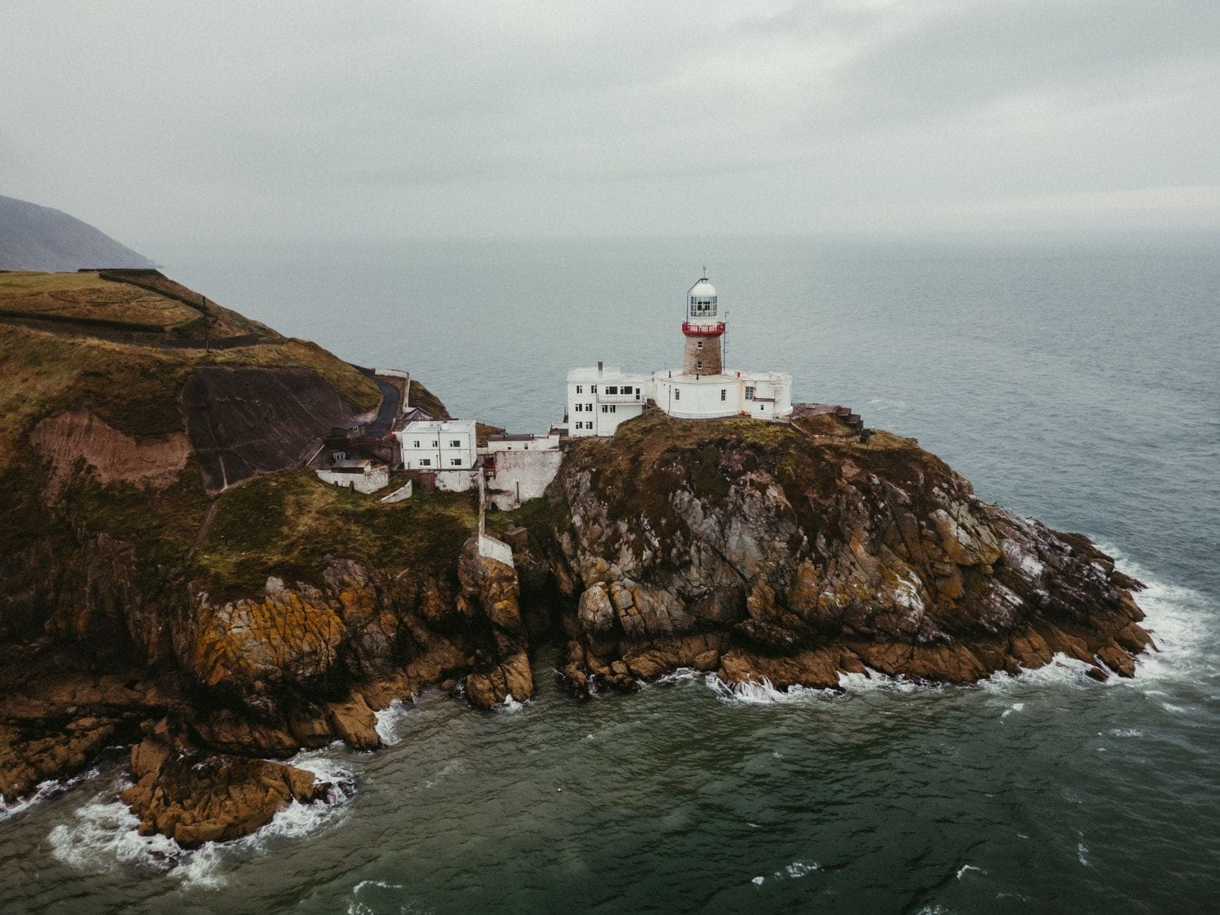 Un drammatico faro arroccato su scogliere rocciose che si affacciano sull'oceano vicino a Dublino, esempio perfetto di passeggiate costiere e sentieri sulle scogliere.