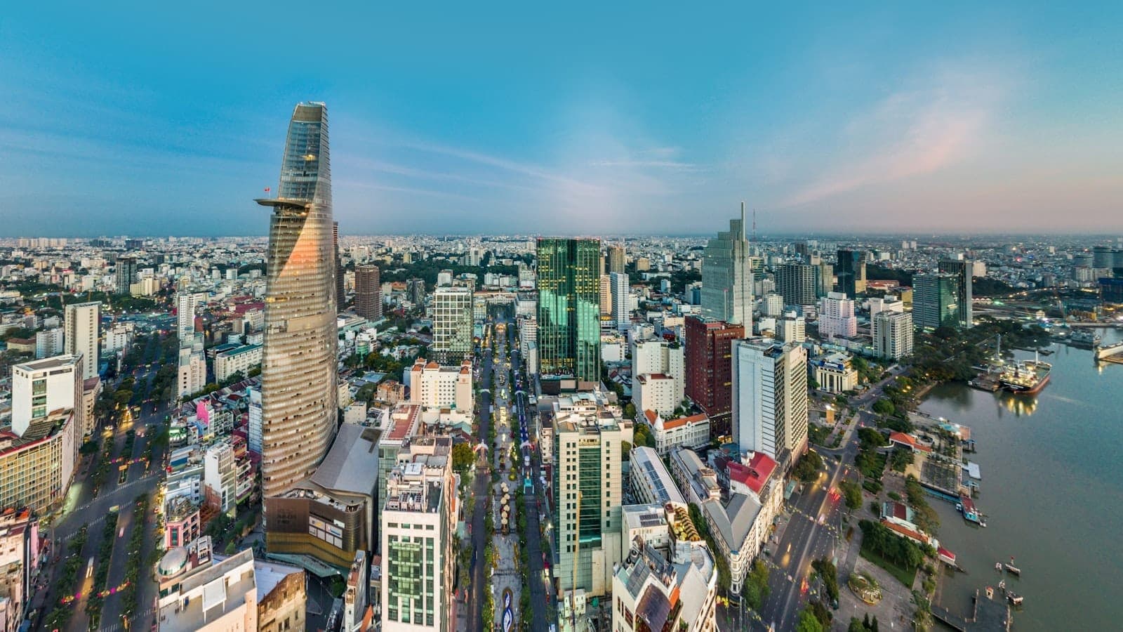 Toàn cảnh TP. Hồ Chí Minh từ trên cao với tháp Bitexco, các tòa nhà cao tầng hiện đại, sông Sài Gòn và những con phố nhộn nhịp dưới bầu trời xanh trong.