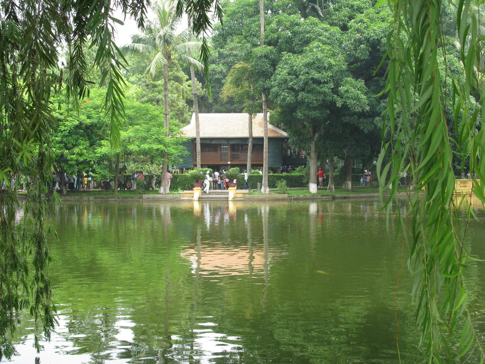 Nhà Sàn của Hồ Chí Minh, một ngôi nhà gỗ giản dị, đứng bên cạnh một hồ nước yên tĩnh được bao quanh bởi những cây xanh tươi tốt tại Hà Nội.