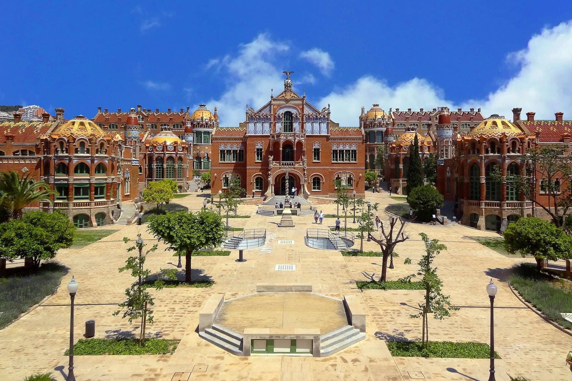 Toàn cảnh khu phức hợp Hospital de Sant Pau ở Barcelona dưới bầu trời xanh trong, nổi bật với kiến trúc Modernista, những mái vòm và sân trung tâm.