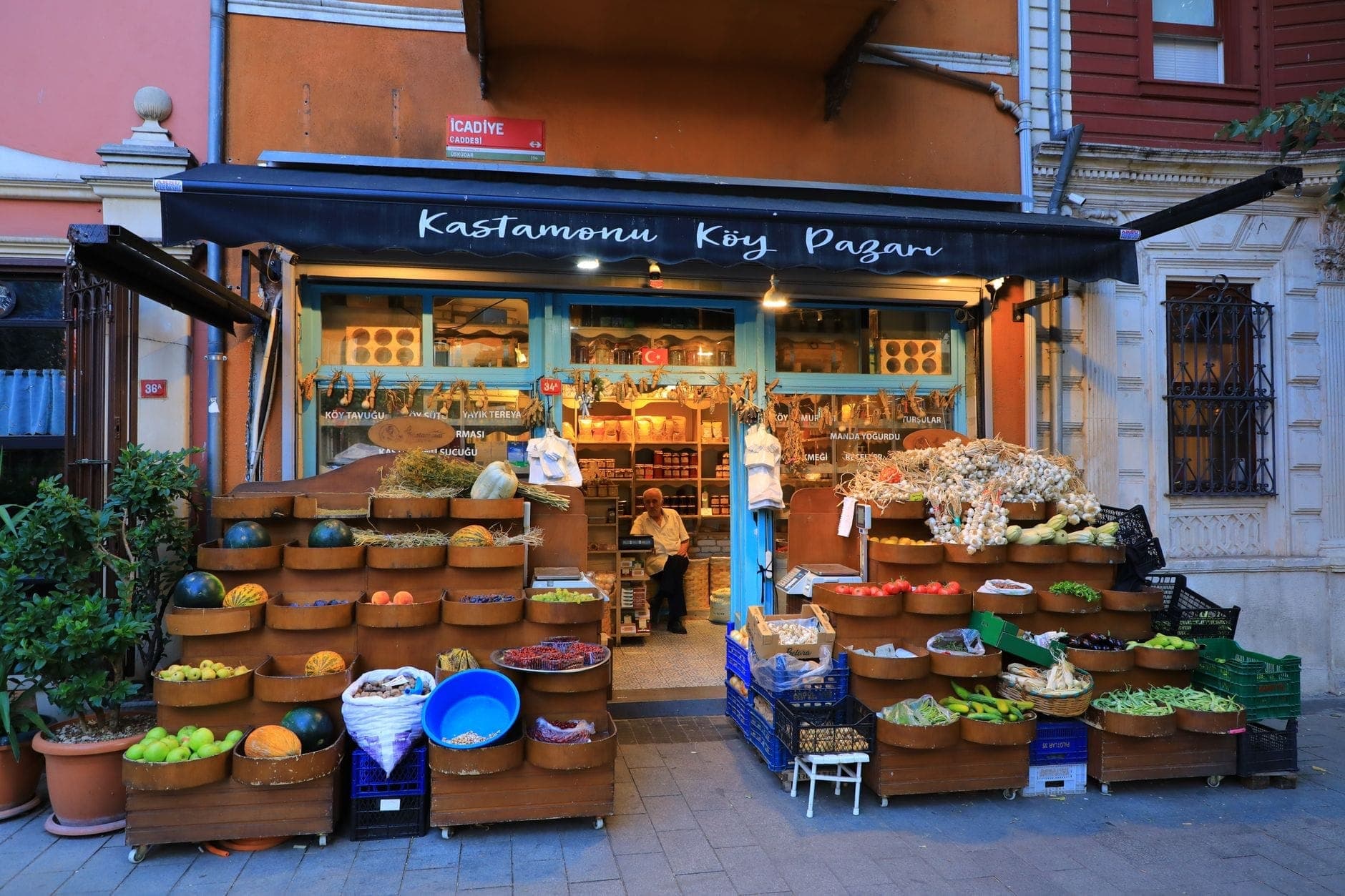 Eine bunte Ladenfront in Kadıköy, Istanbul, mit Körben voller Produkte, Gewürze und Waren sowie einer Person in dem einladenden, gut beleuchteten Geschäft.